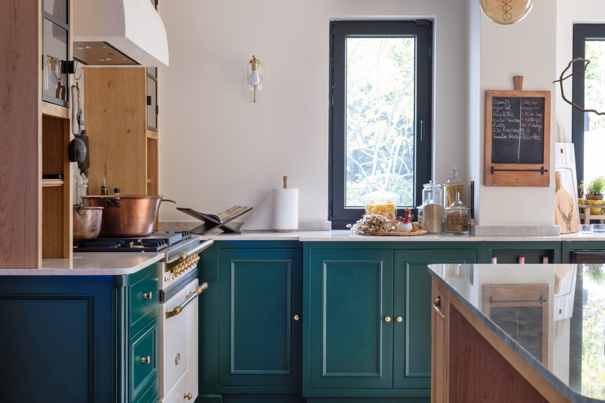 A kitchen with green cabinets and a copper pan on the hob