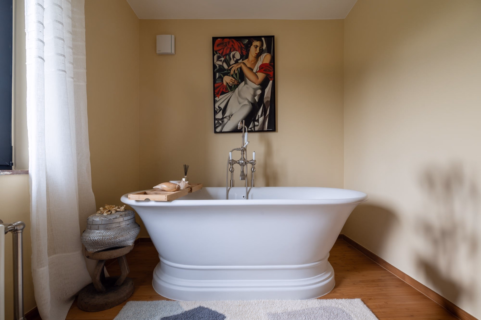 A bathtub with a painting on the wall above it