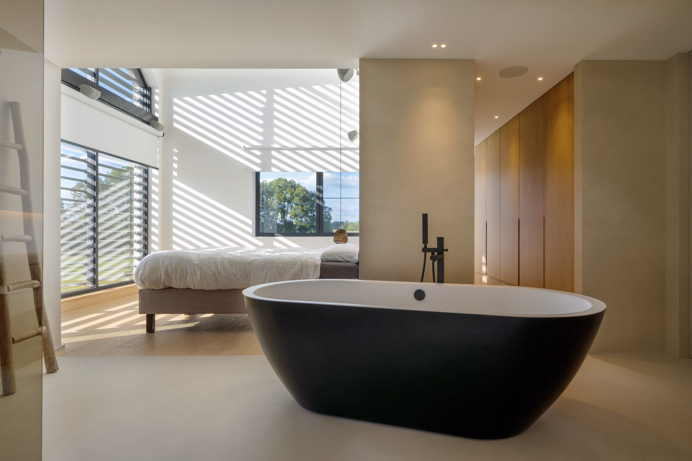 A bathroom with a bathtub, the bed beyond