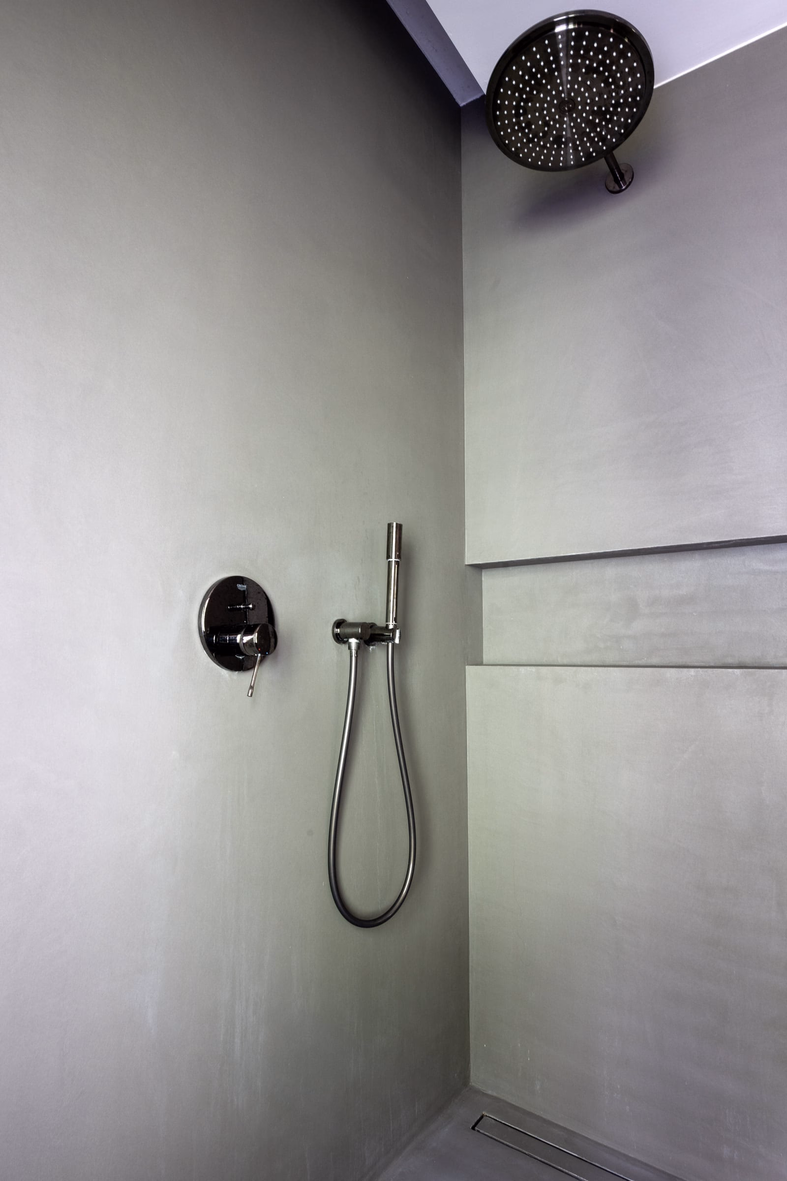 A black shower head on a grey wall