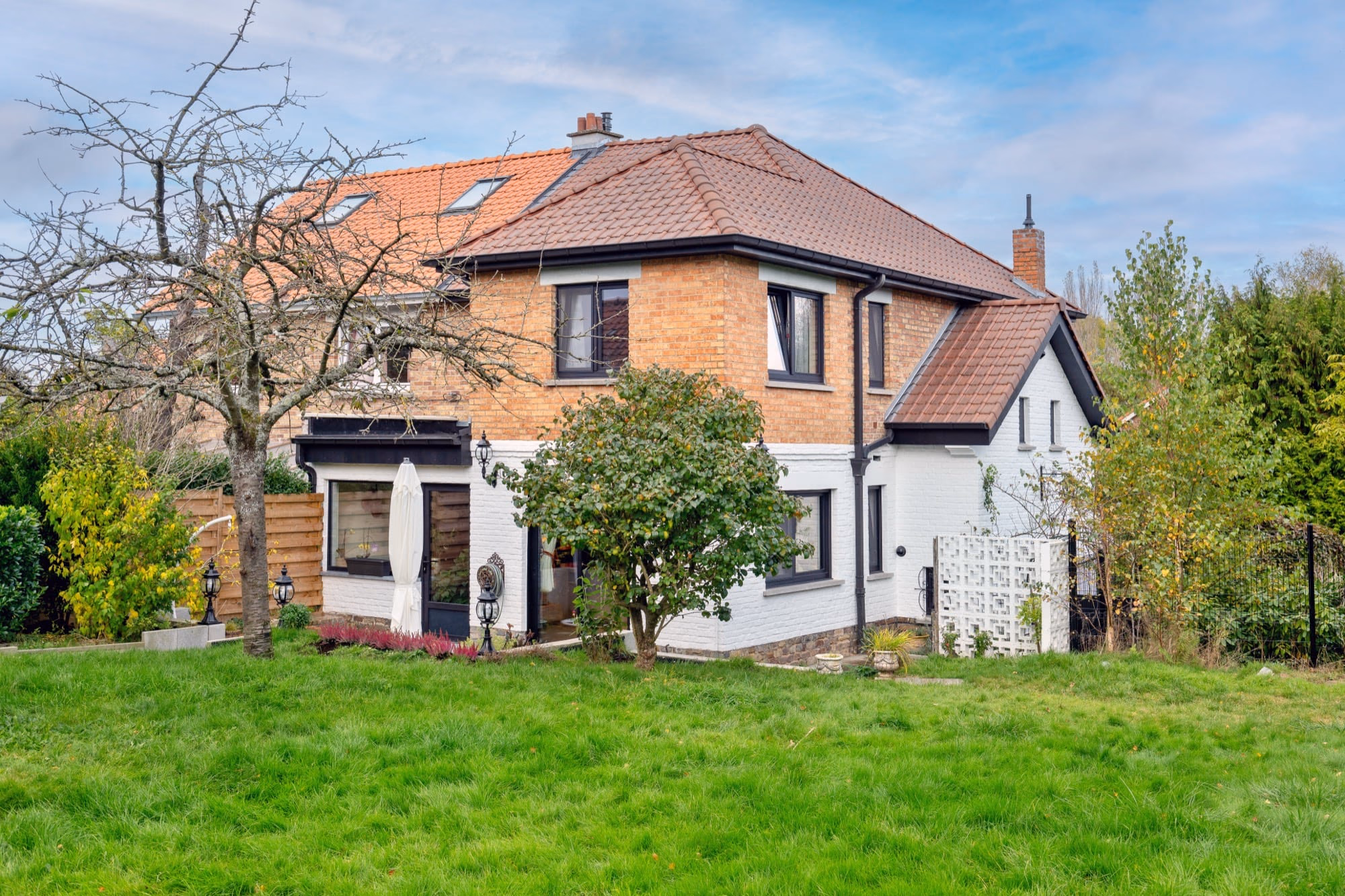 A white house with a red tiled roof beside a brick house
