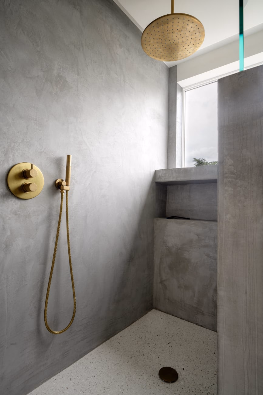 A bathroom with a brass shower head and a window