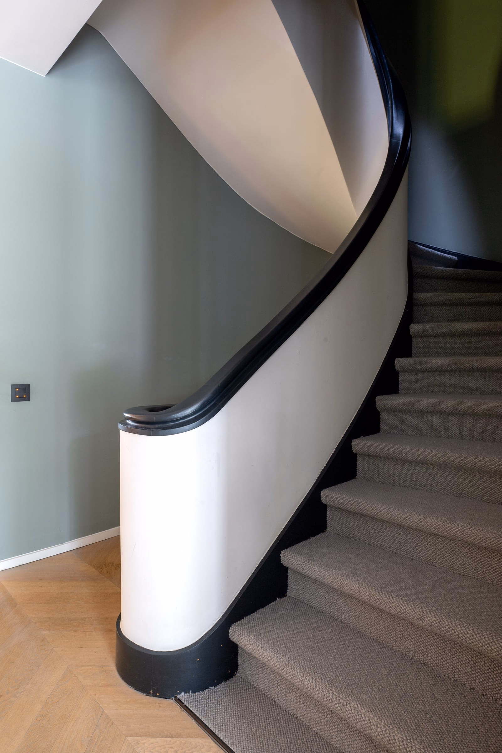 A staircase with a white balustrade and a black handrail