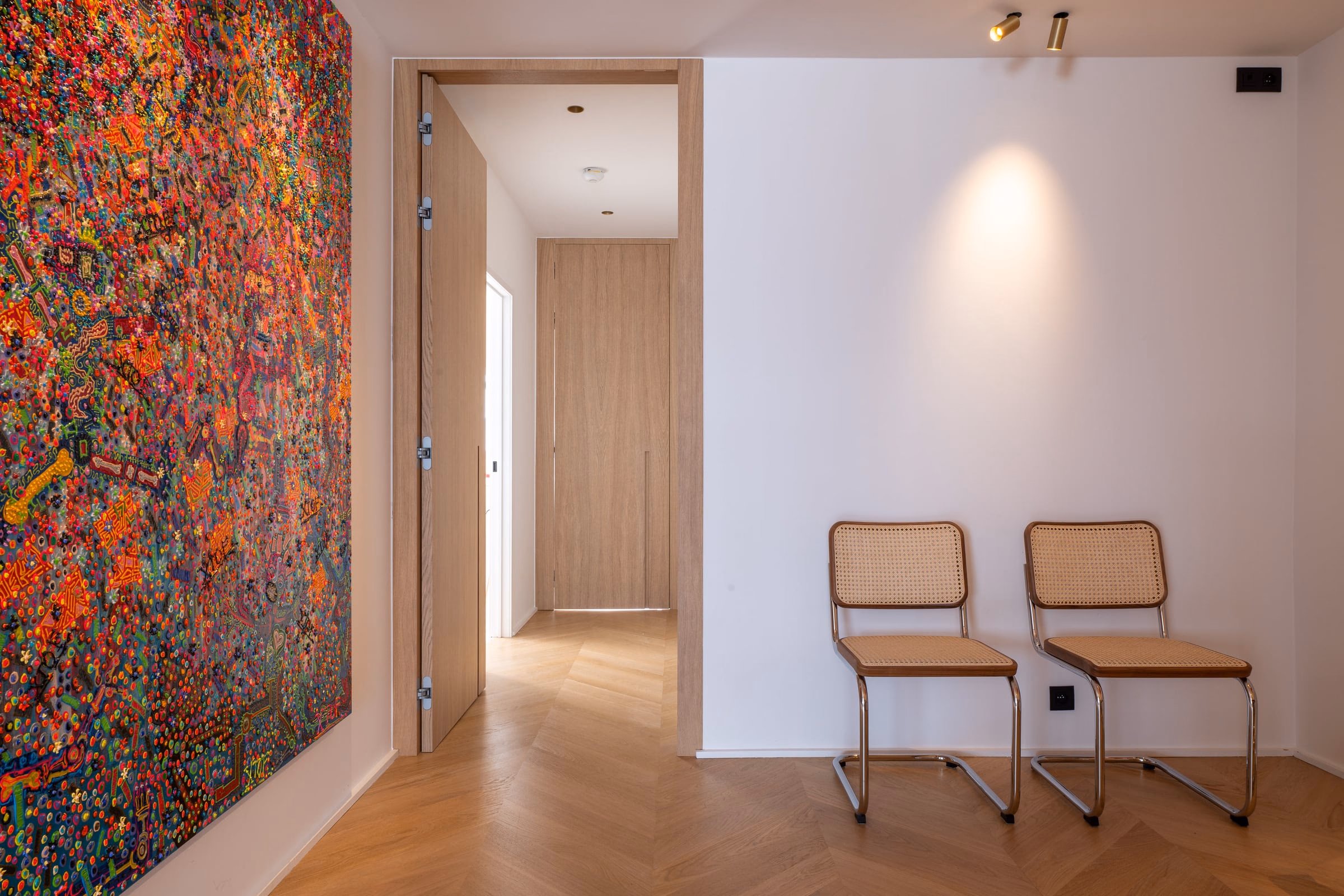 A hallway with two chairs and a painting on the wall