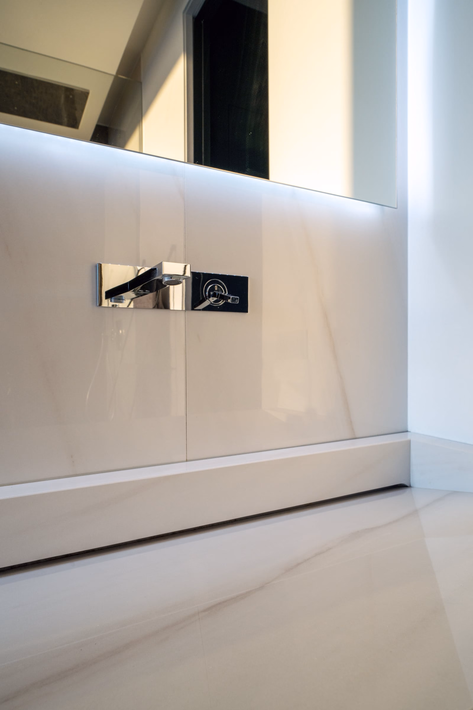A bathroom wall with a tap and a mirror