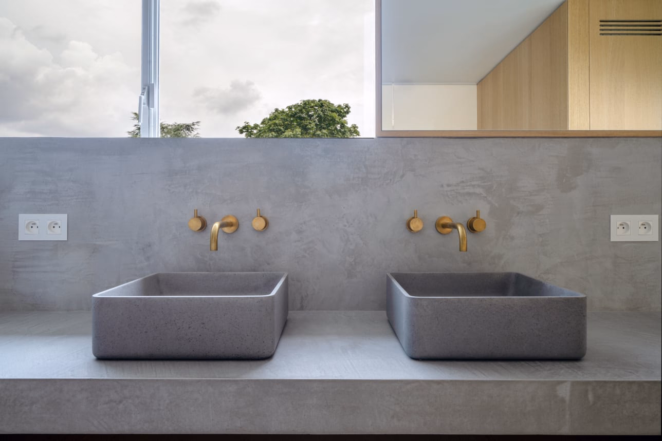 A bathroom with two washbasins and brass taps