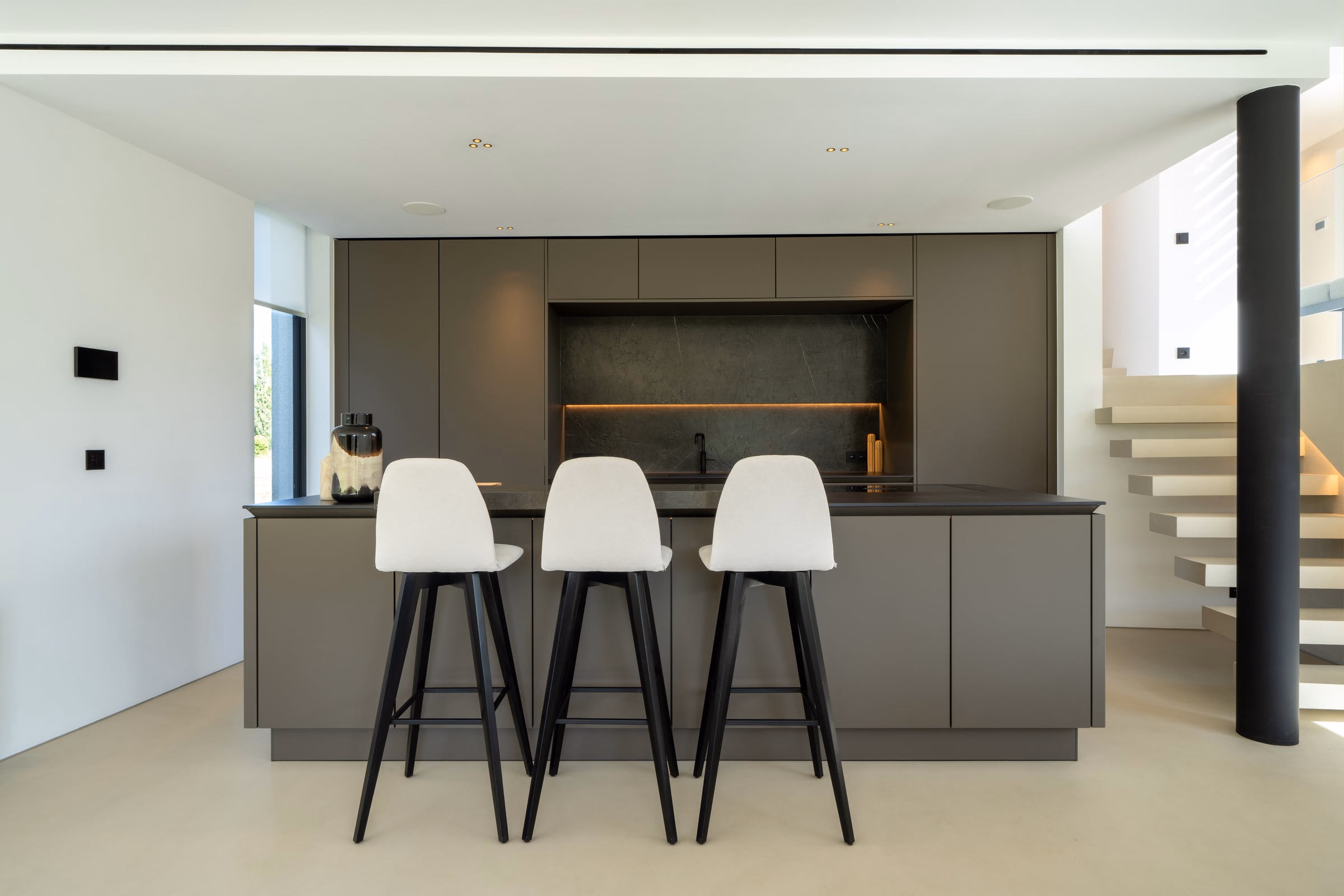 Three white bar stools in a kitchen