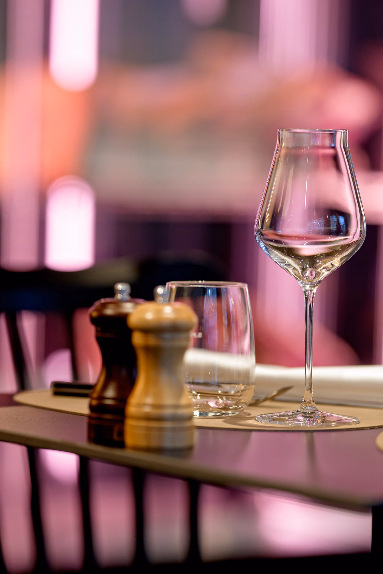 A wine glass beside salt and pepper on a table
