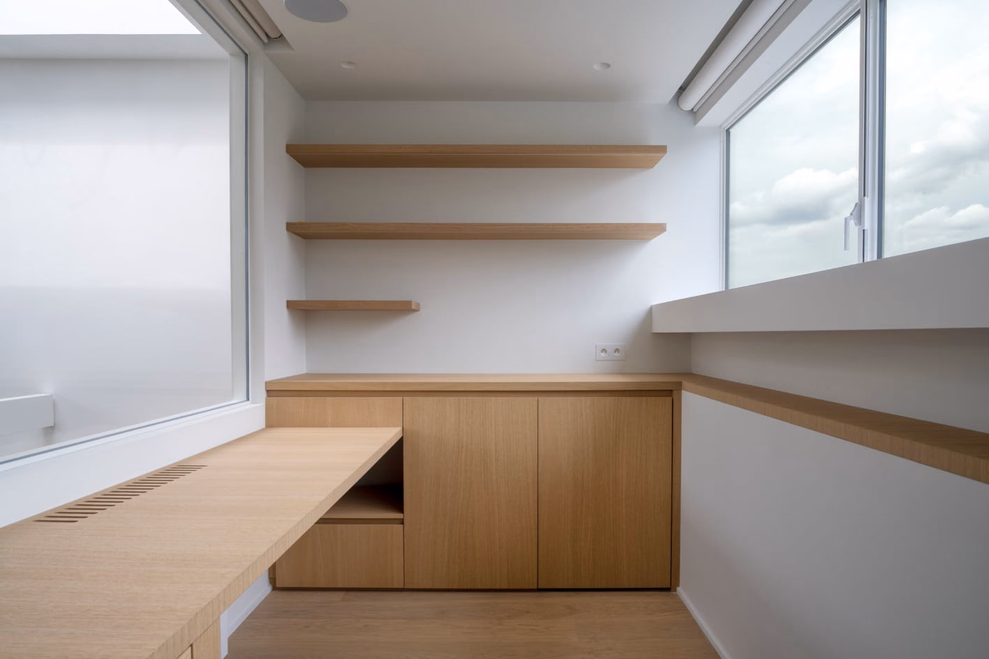 A corner of a room with wooden cabinets and shelves