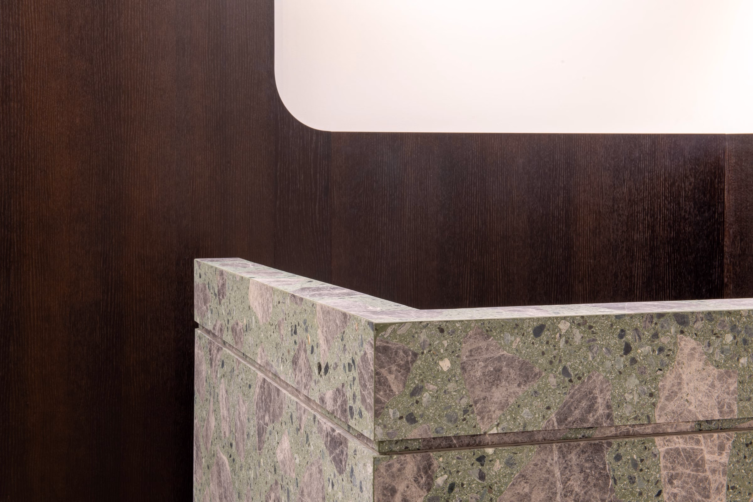 A green and brown marble counter against a wooden wall