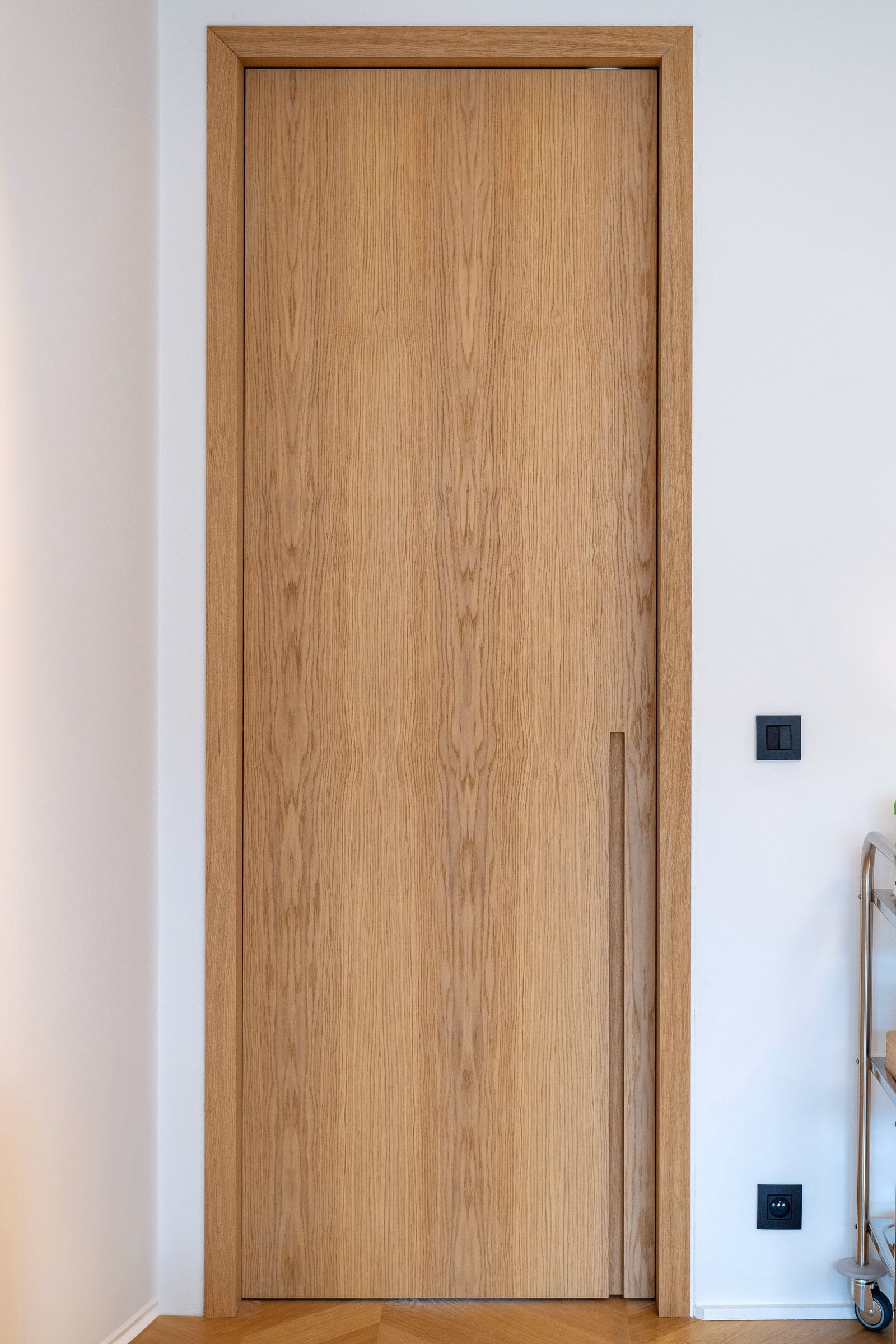 A wooden door with a black switch on the wall