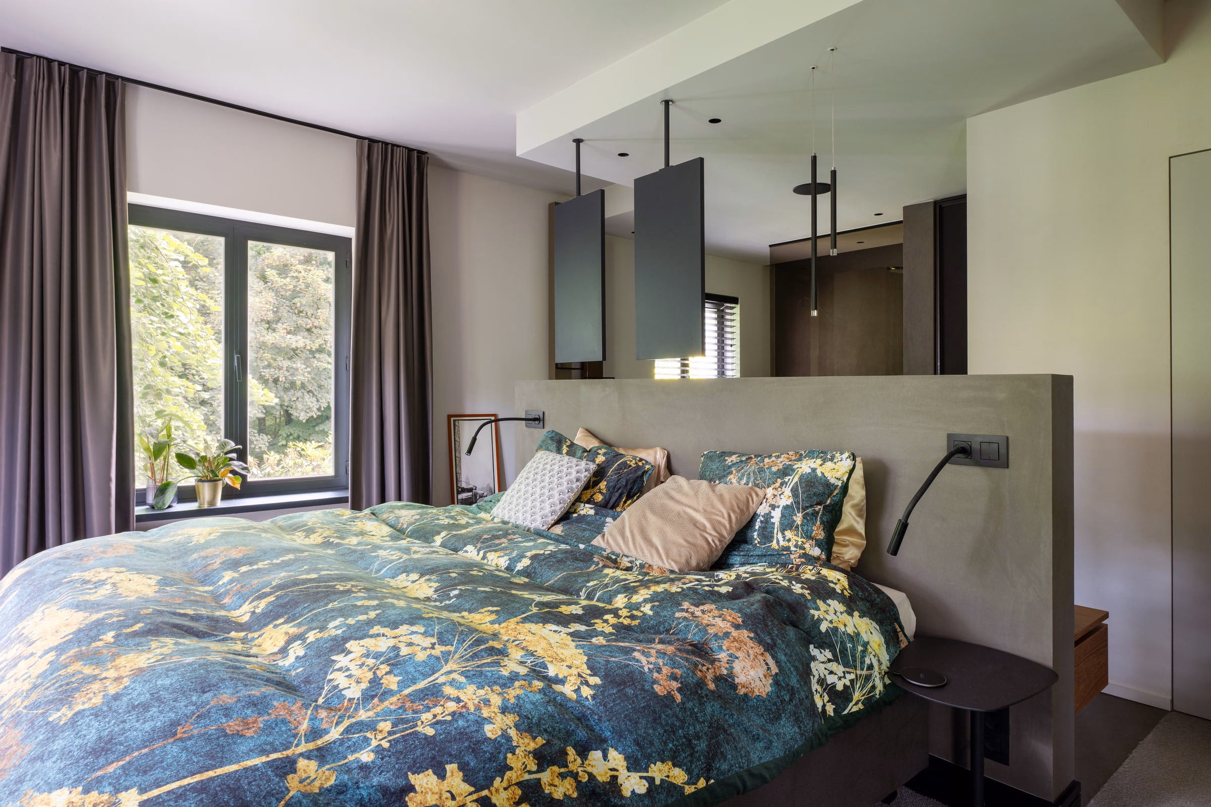 A bed with a floral bedspread and cushions