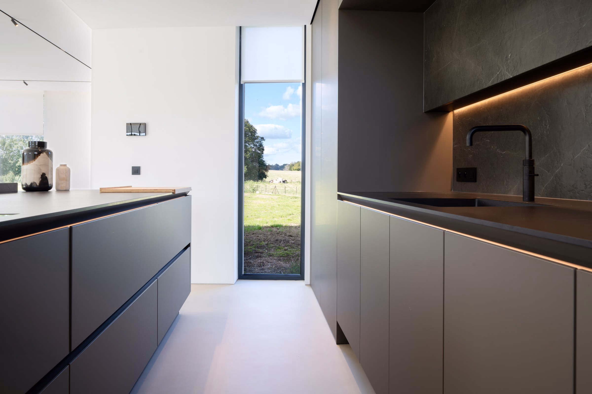 A kitchen with black cabinets and a large window