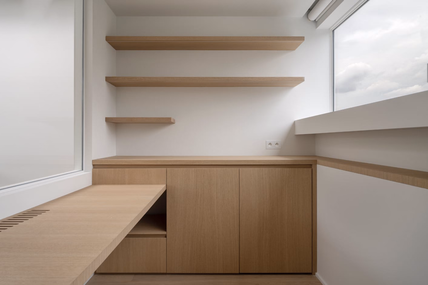 A corner of a room with wooden cabinets and shelves