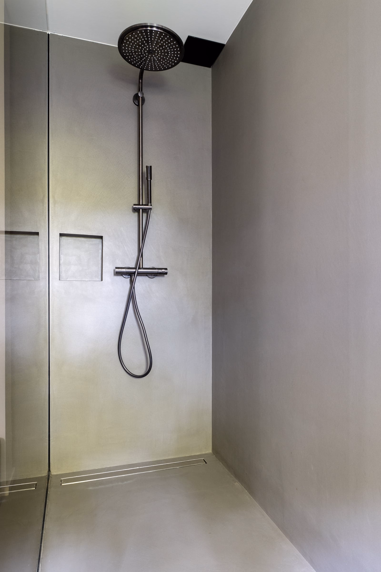 A shower with a stainless steel shower head and hose