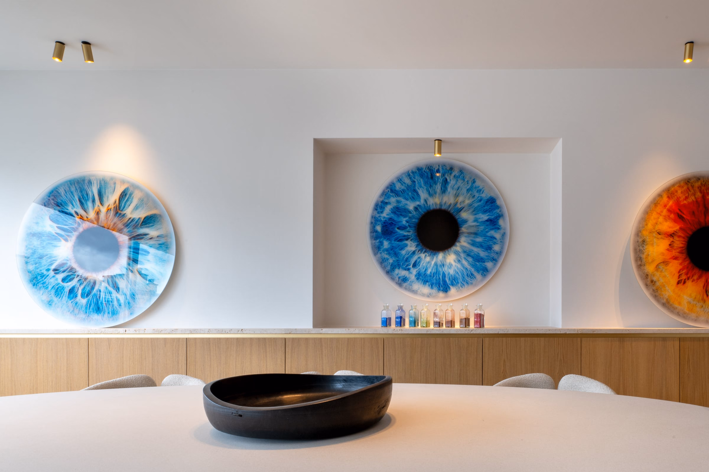 A black bowl on a table before a painting of an eye
