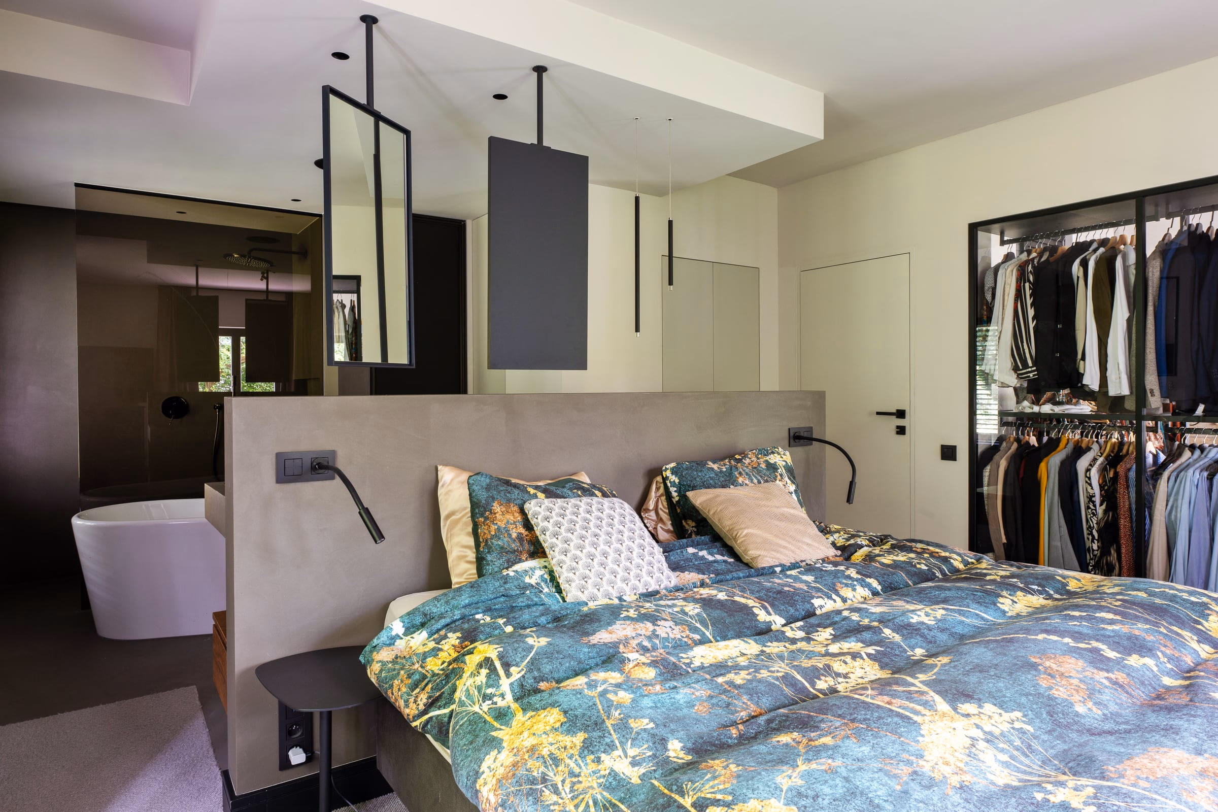 A bed with a floral bedspread and cushions