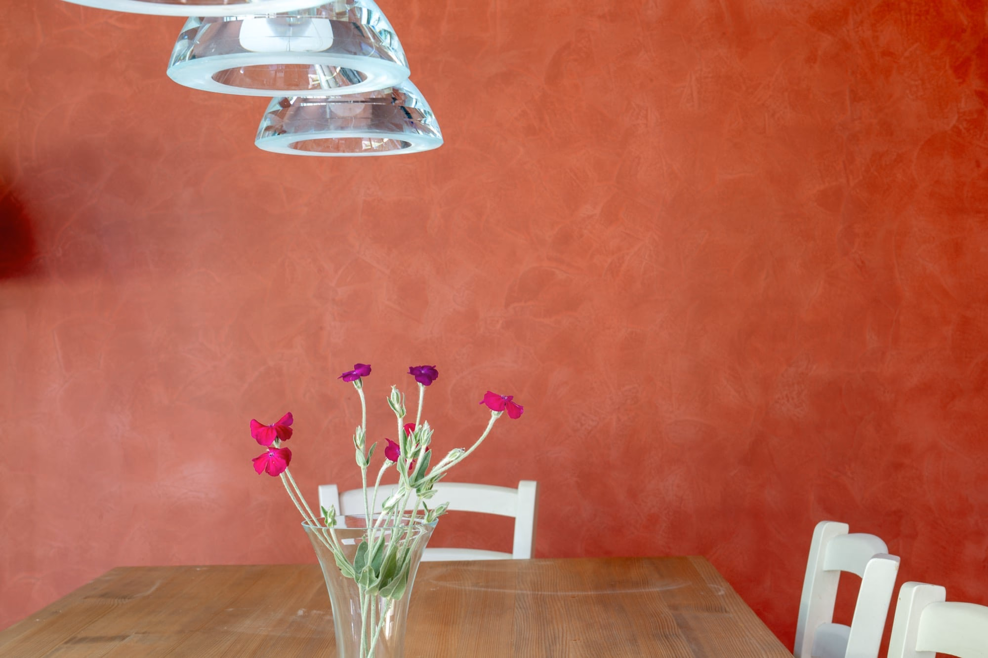 A vase of flowers on a table against a red wall