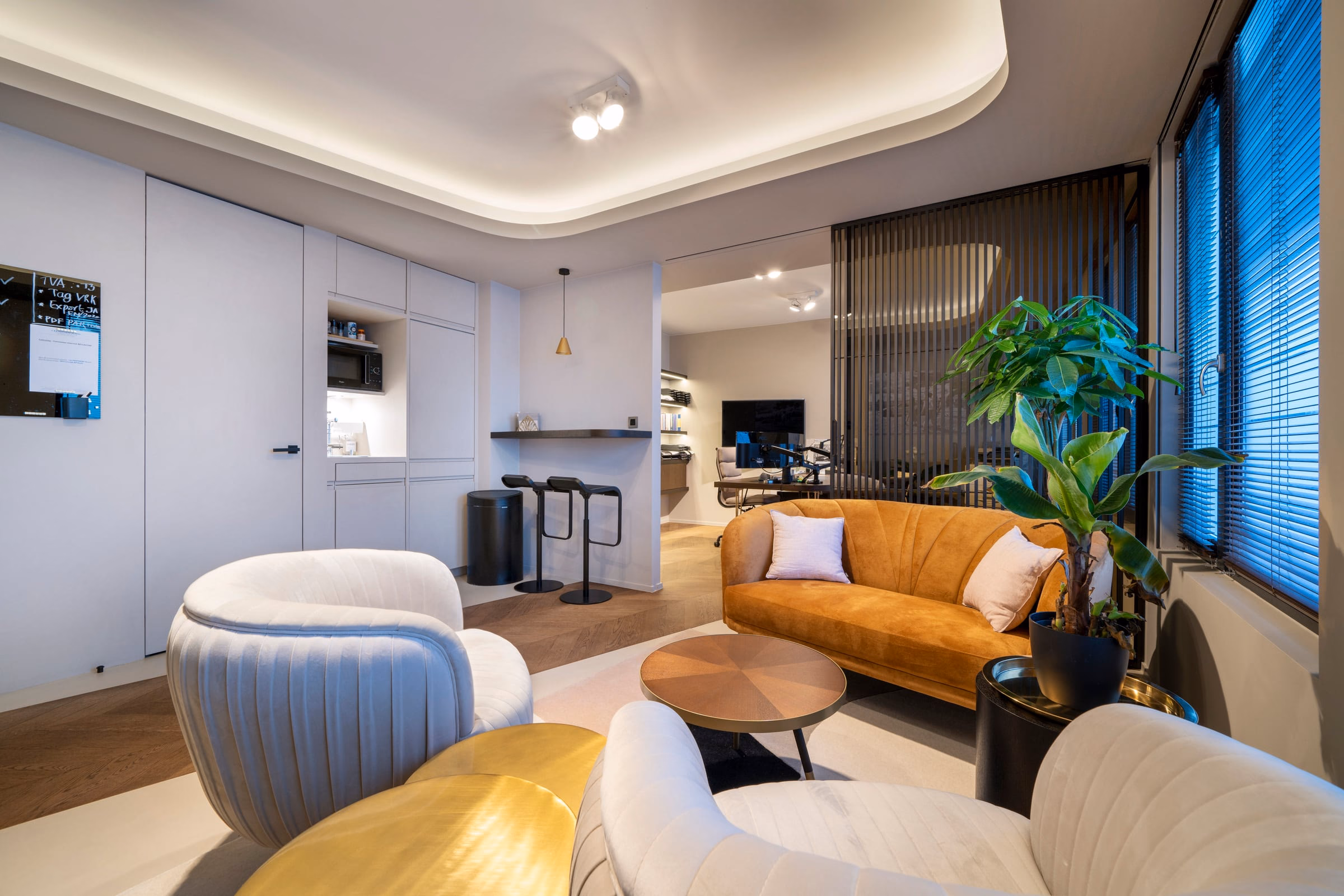 A living room with a brown sofa and white chairs