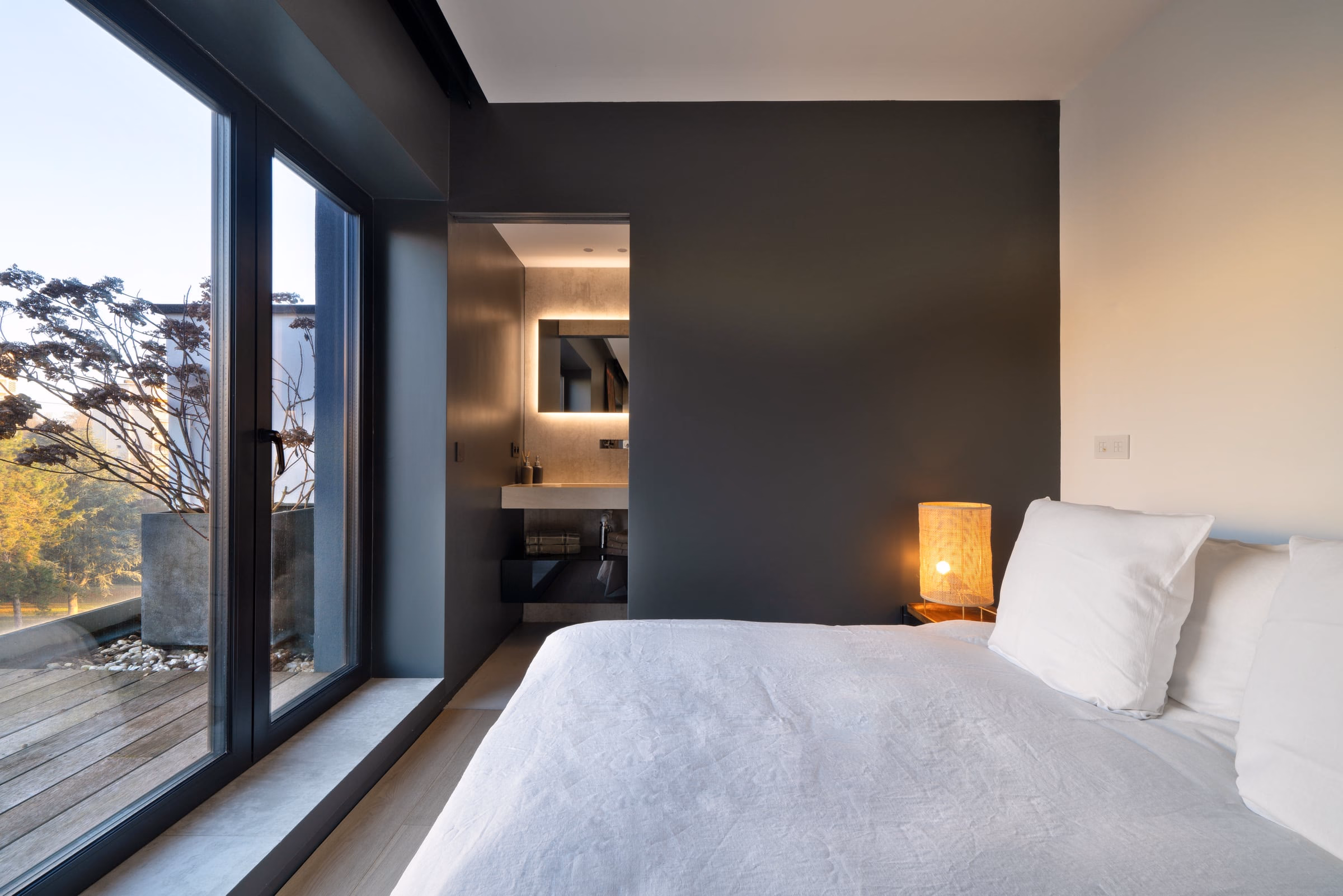 A bedroom with a black wall and a white bed