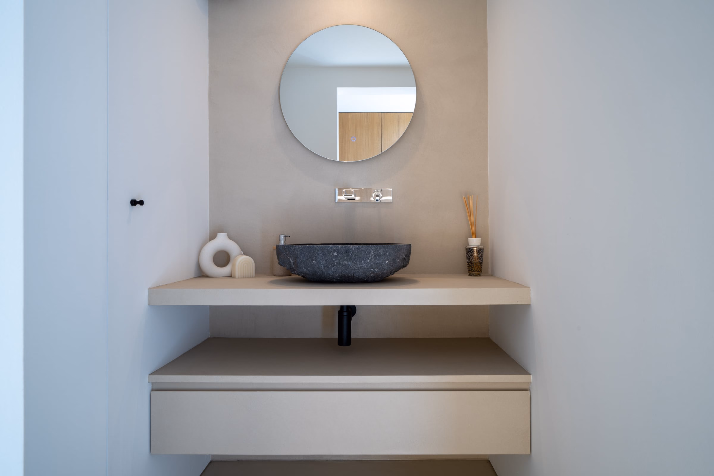 A bathroom with a round mirror above a washbasin