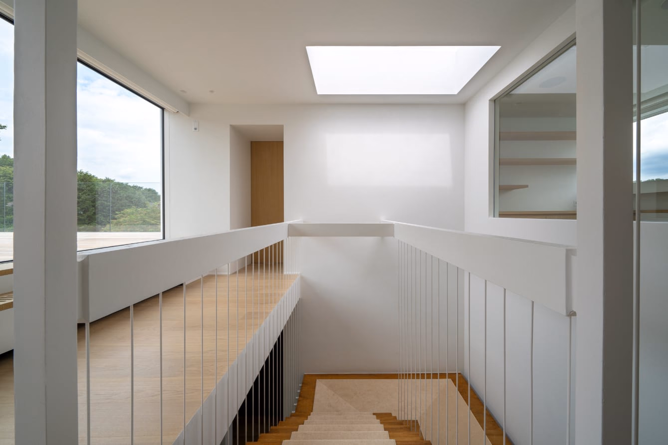 A staircase with a white balustrade beneath a skylight
