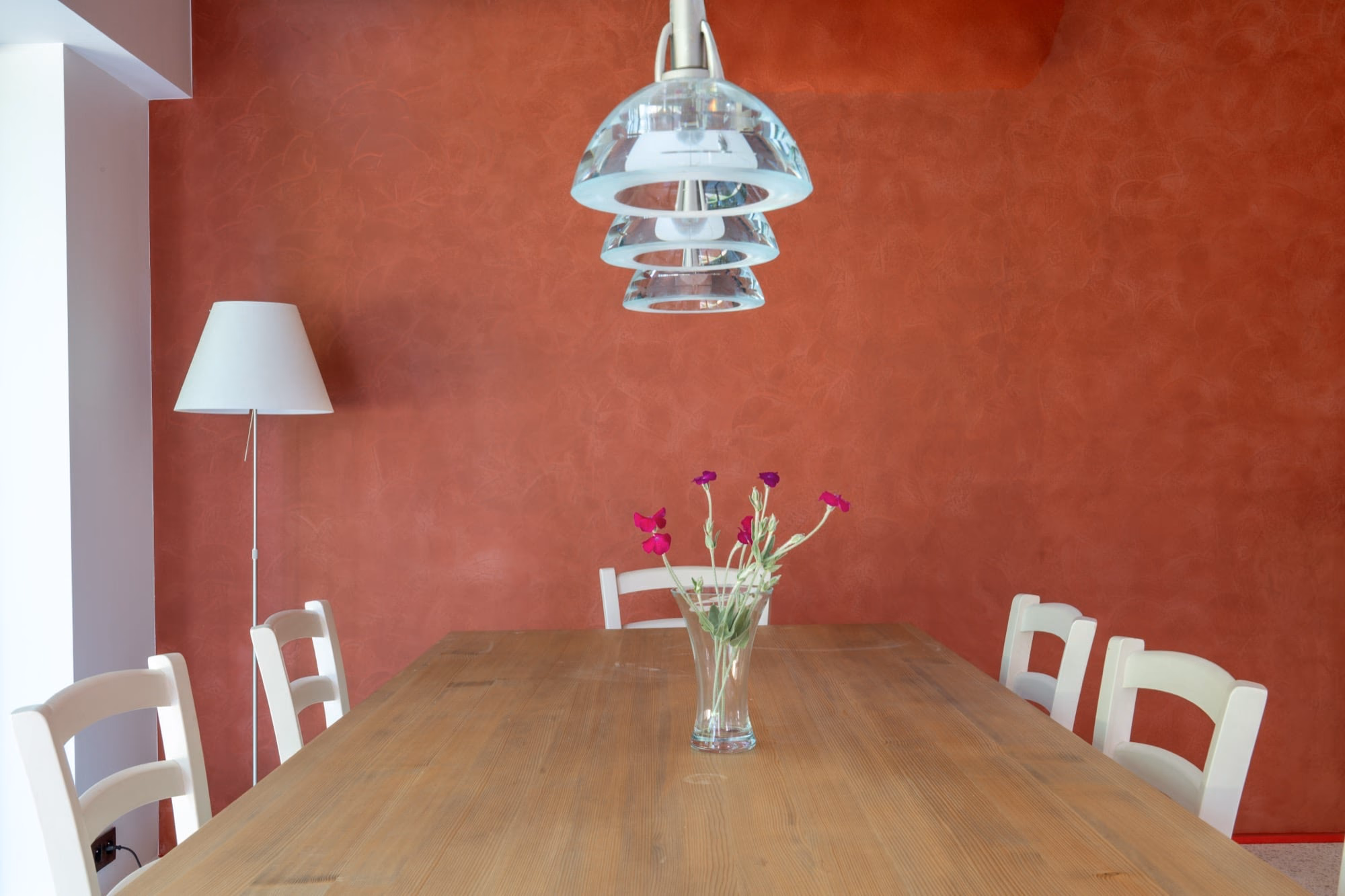 A vase of flowers on a wooden table against a red wall