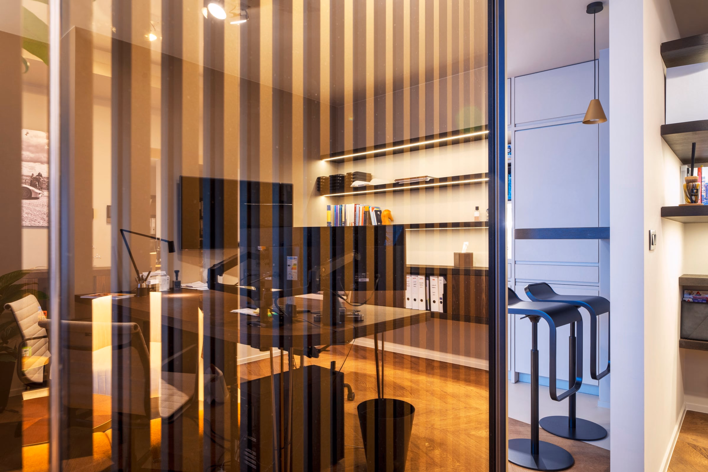 A desk with a computer behind a glass wall