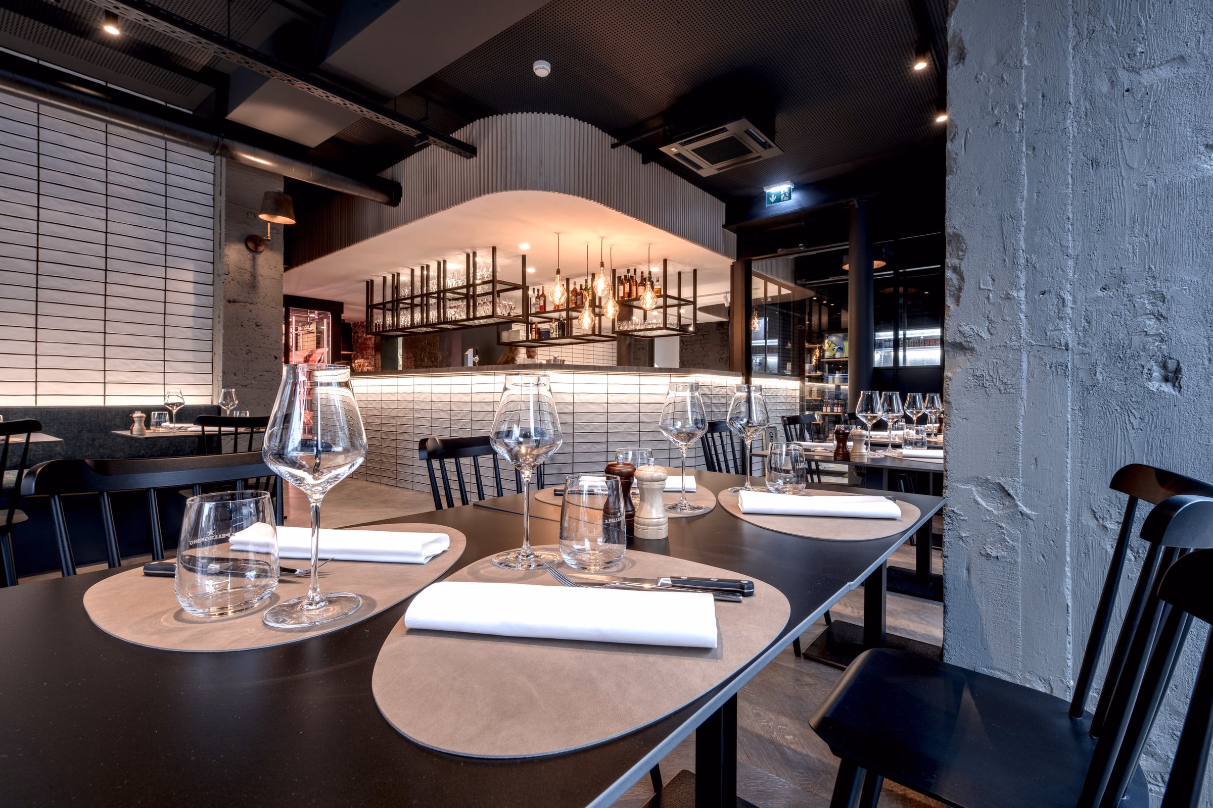 A restaurant with tables laid with wine glasses and napkins