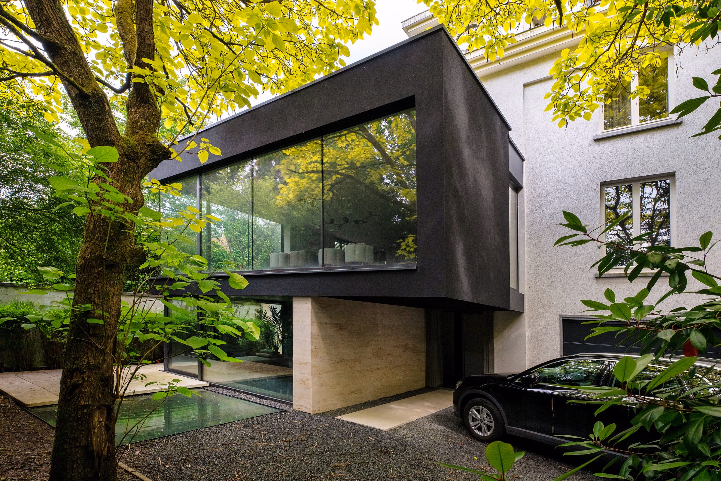 A black car parked in front of a modern house
