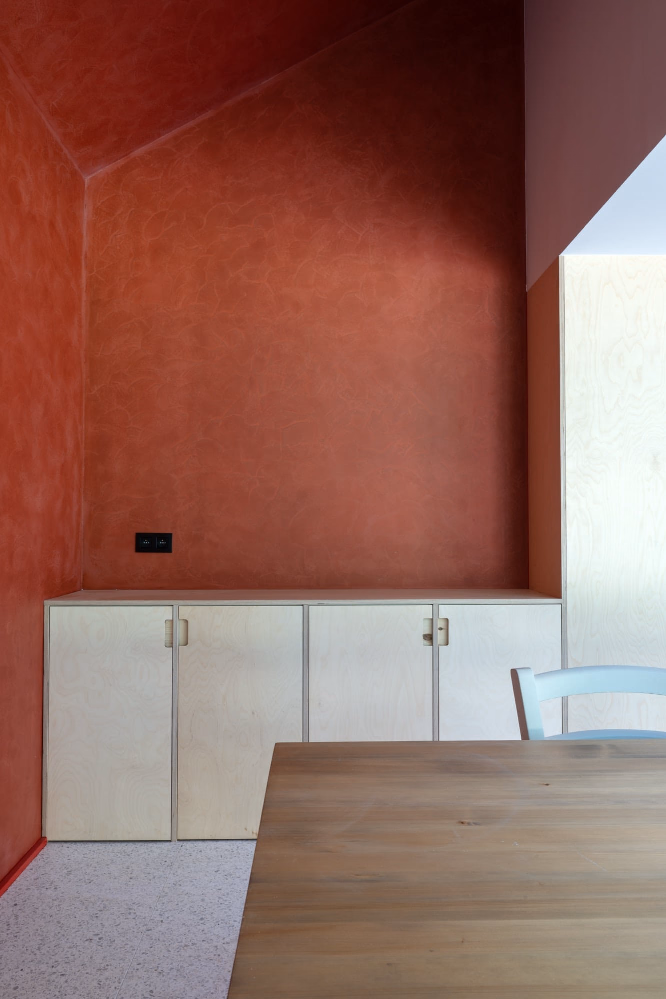 A room with a red wall and white cabinets