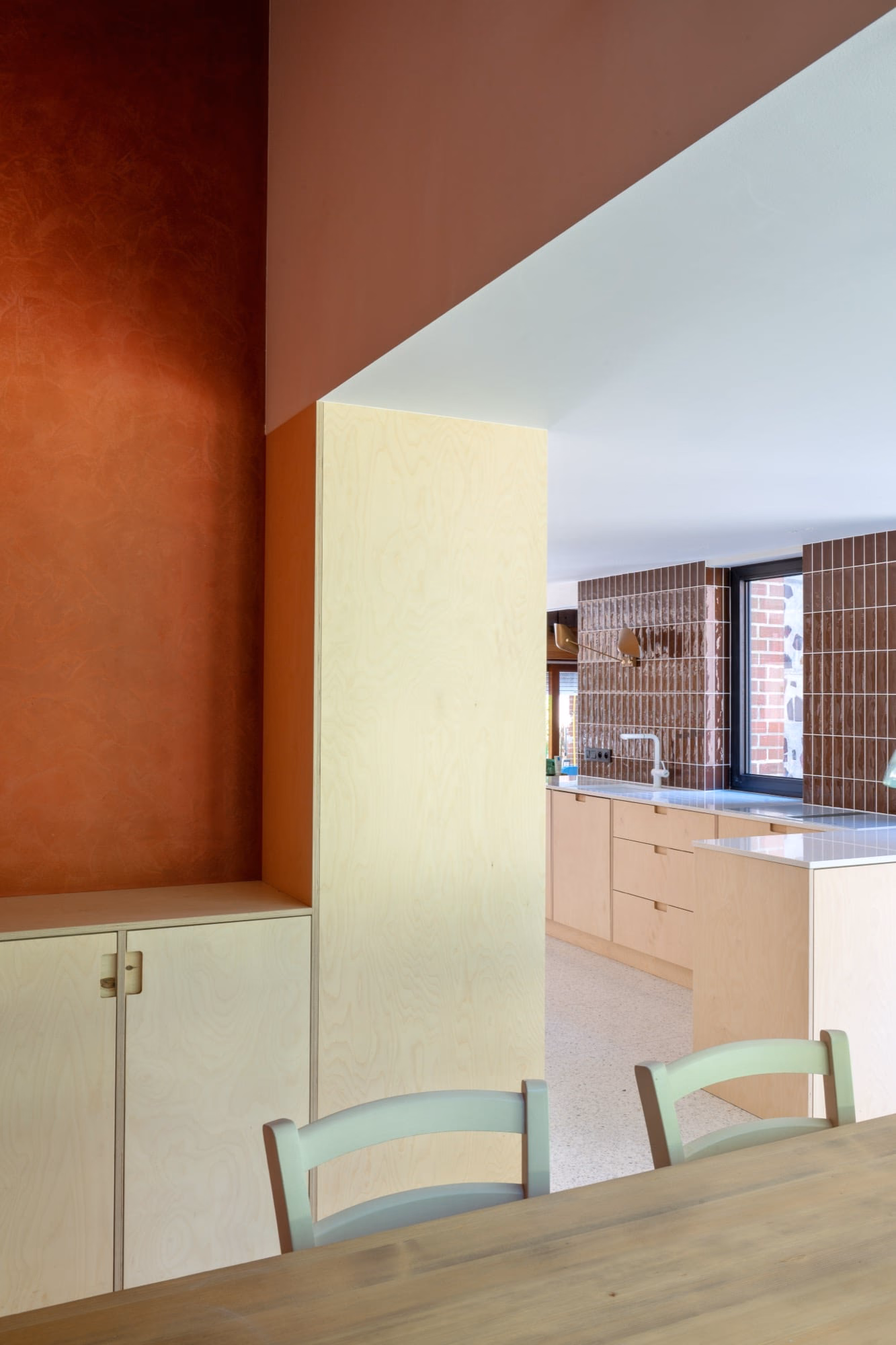 A kitchen with wooden cabinets and a green chair