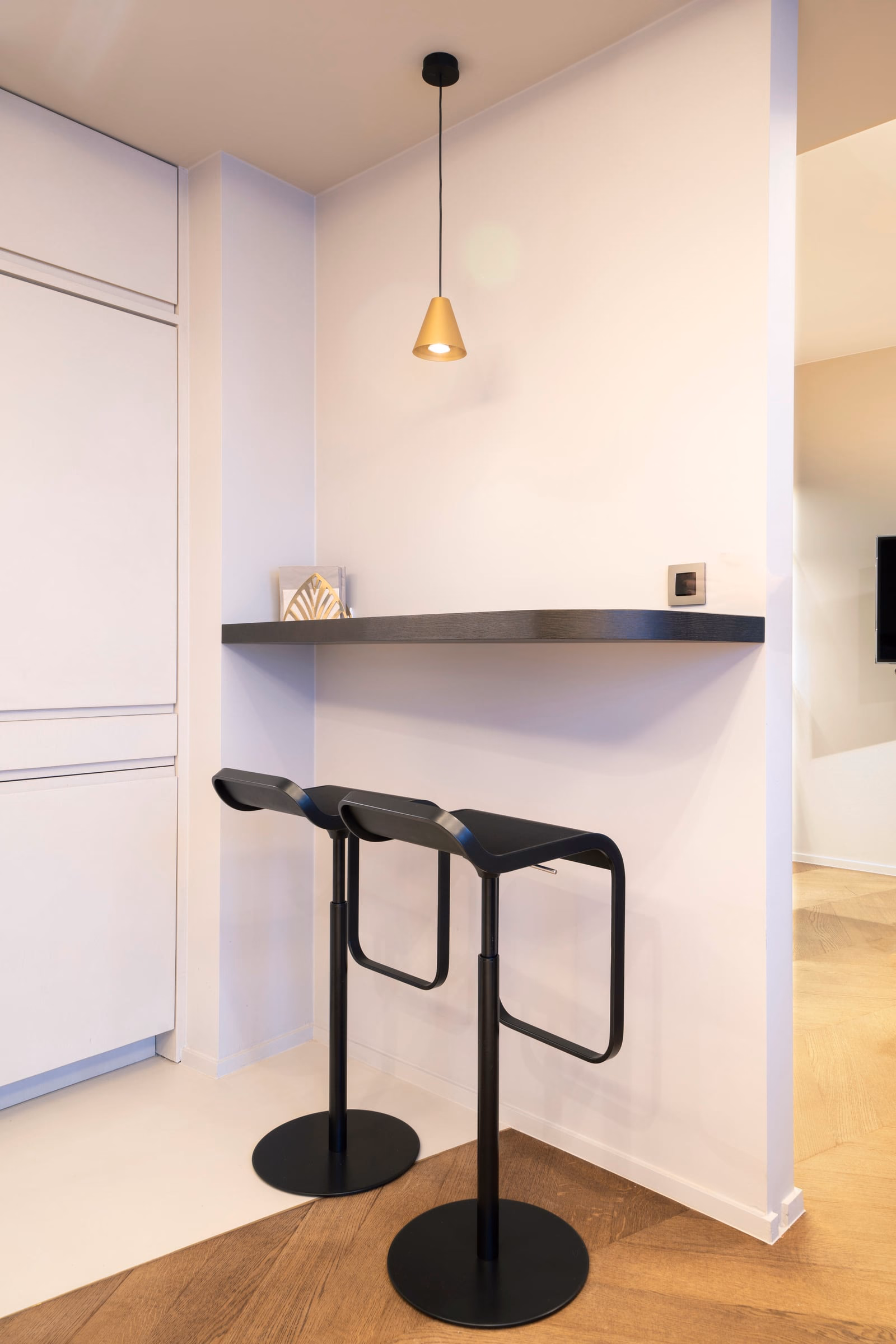 Two black bar stools under a shelf in a kitchen