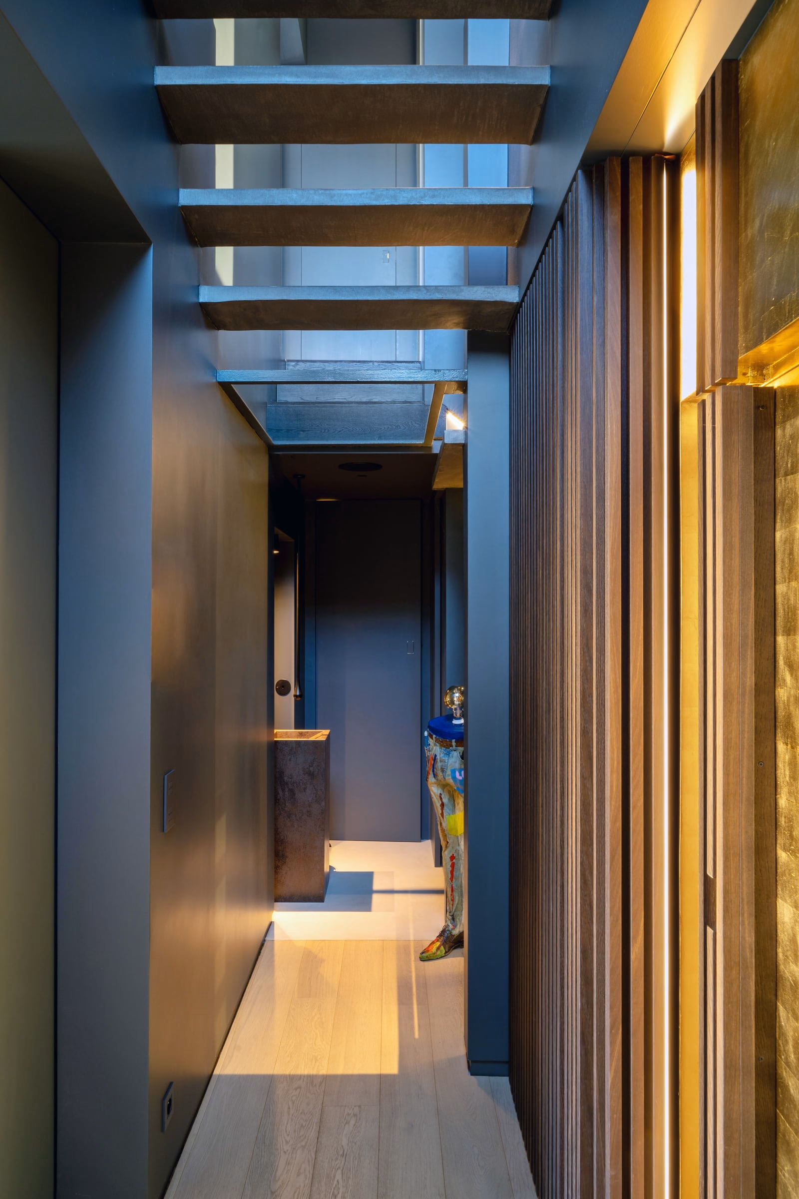 A dark hallway with a staircase and a washbasin