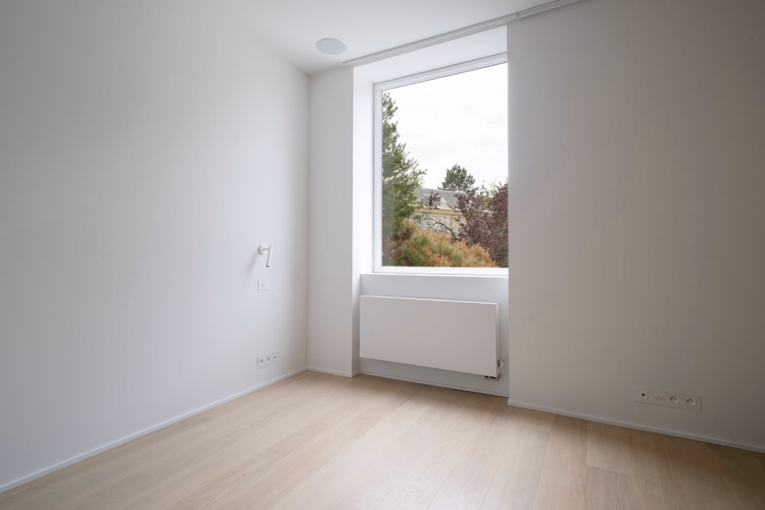 An empty room with a large window and a white radiator