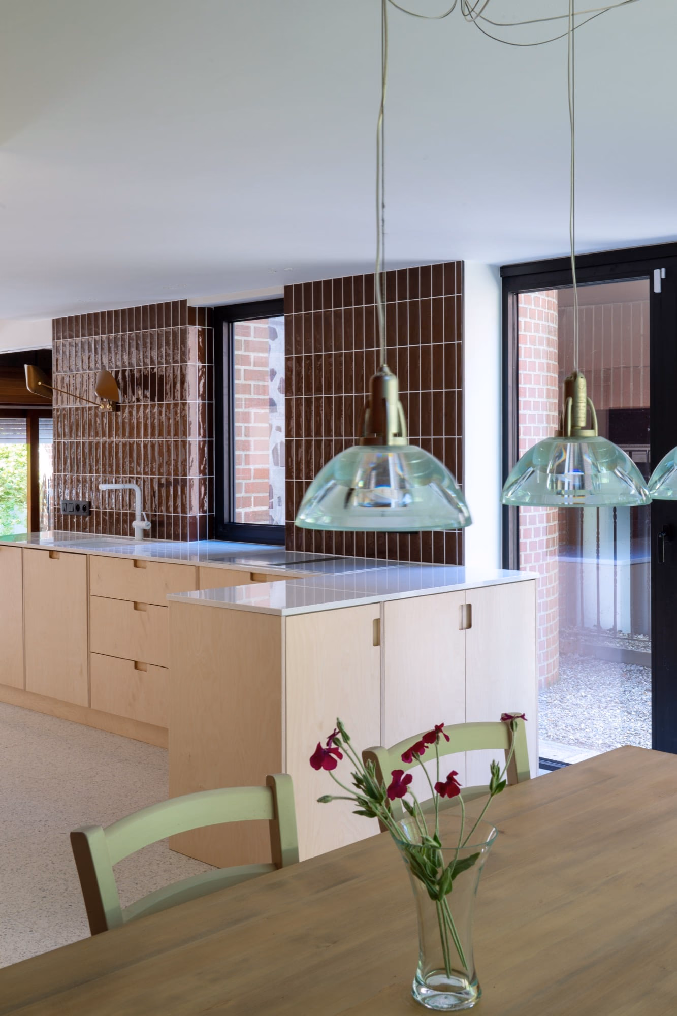 A kitchen with a green chair and flowers on the table
