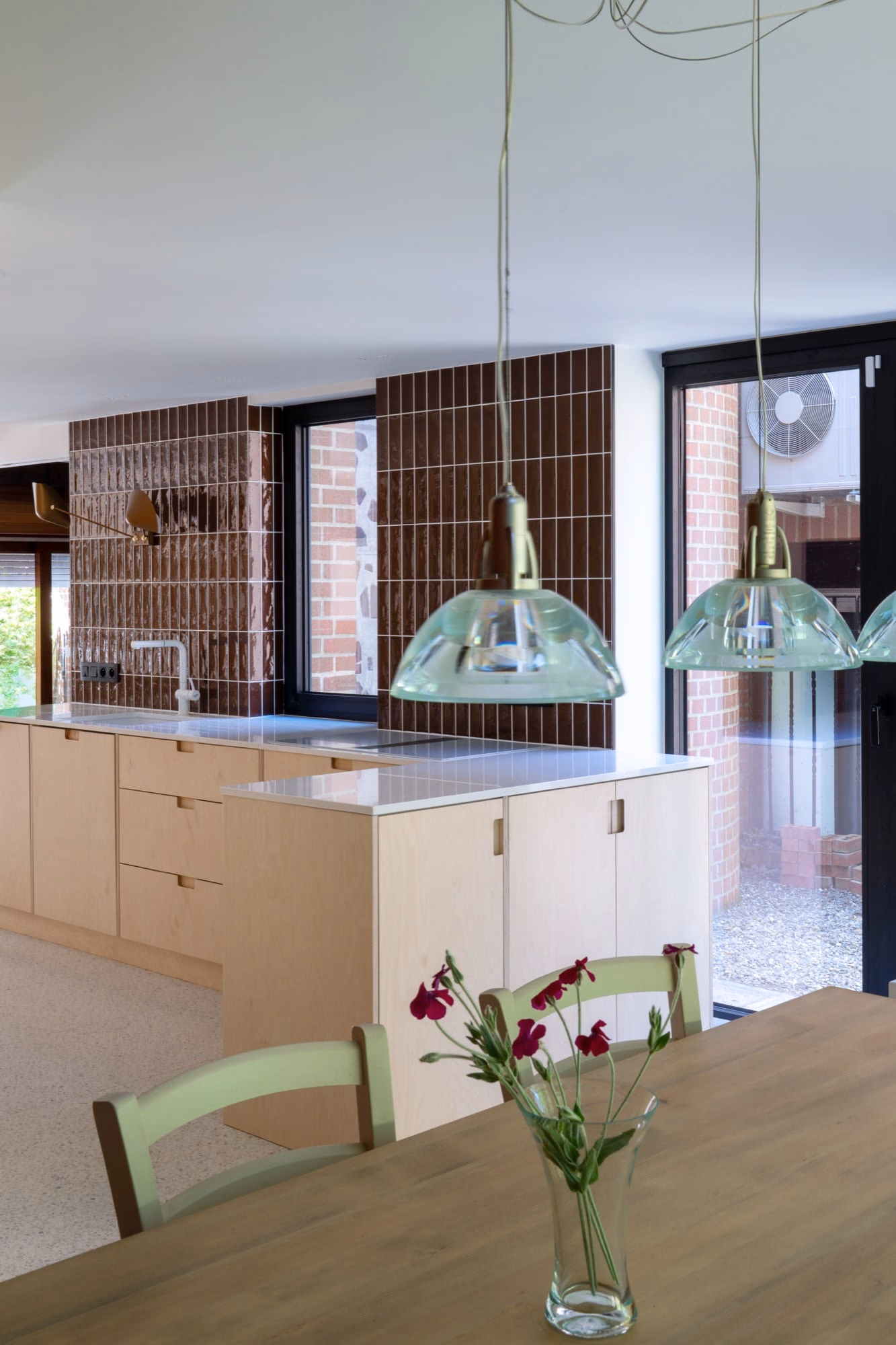A kitchen with a green chair and flowers on the table