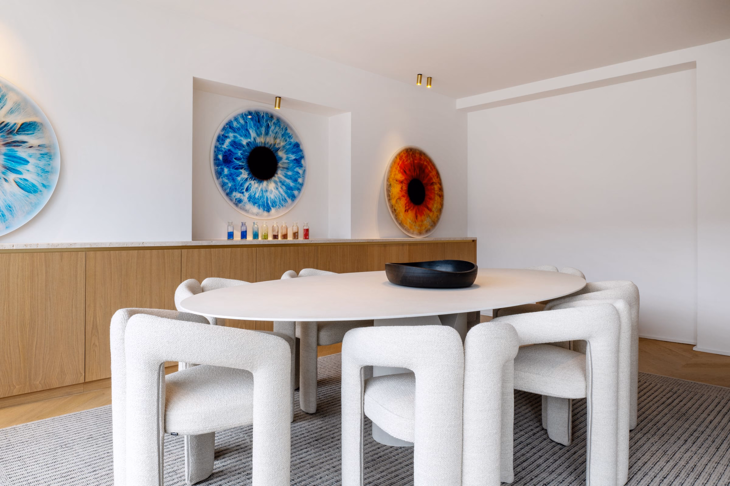 A dining room with a table, chairs and two paintings