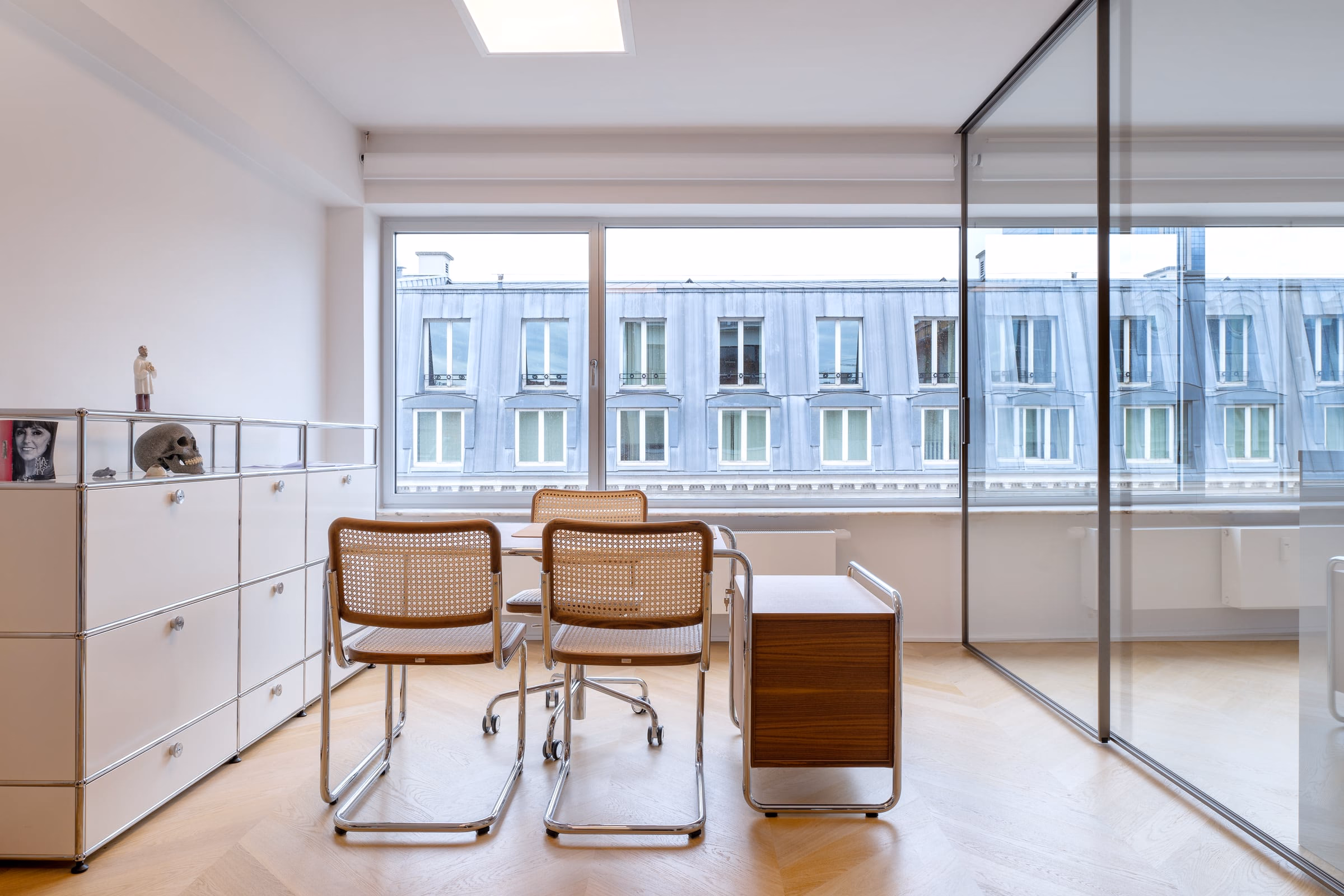 A room with a table and chairs in front of a window
