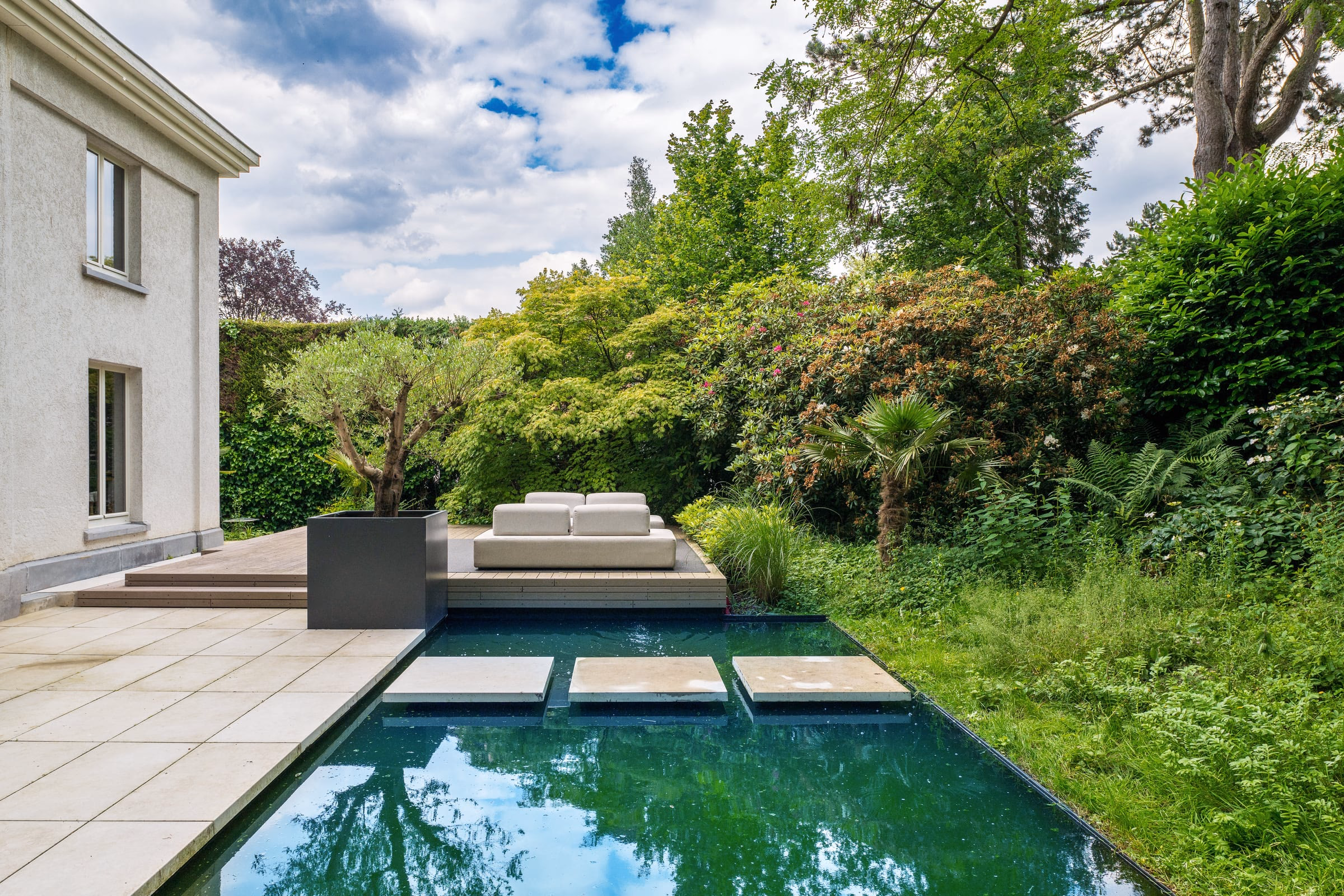A swimming pool with a sofa in the middle of the terrace