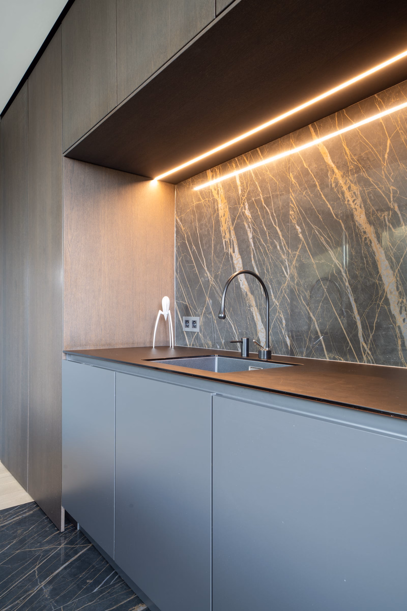 A kitchen sink against a marble wall
