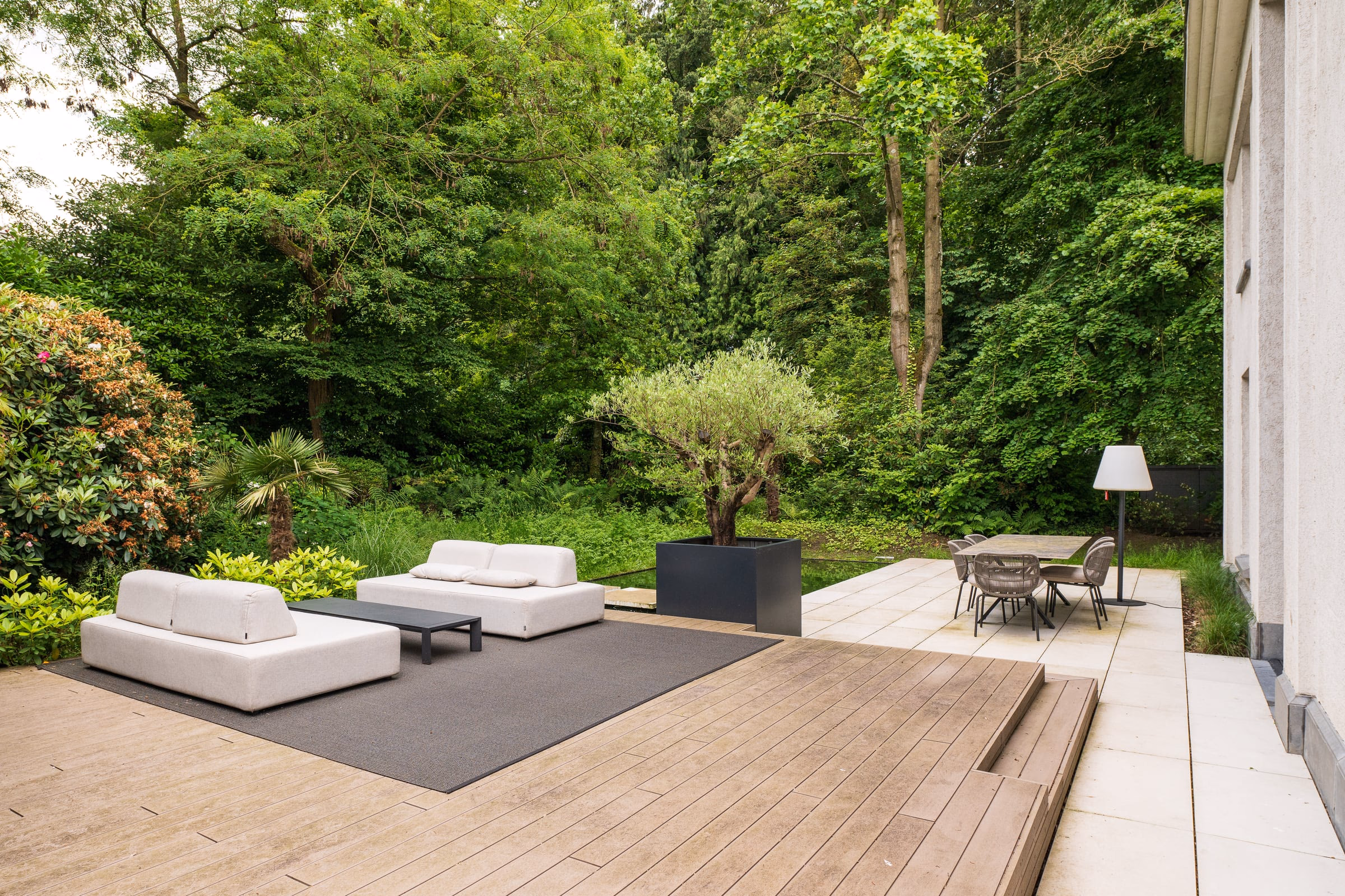 A terrace with a sofa and a table, trees beyond