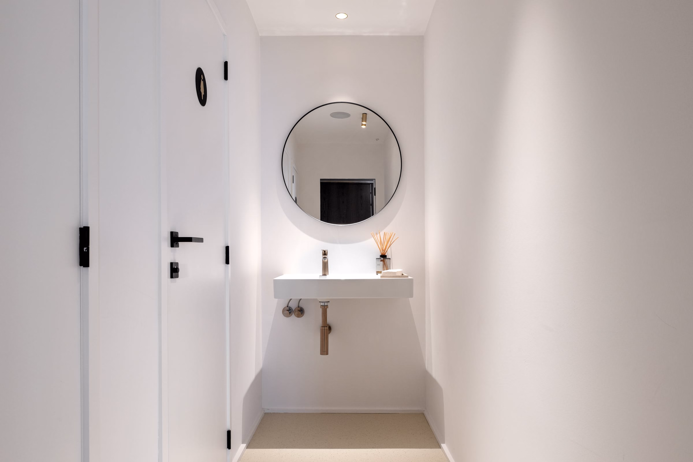 A bathroom with a washbasin and a round mirror