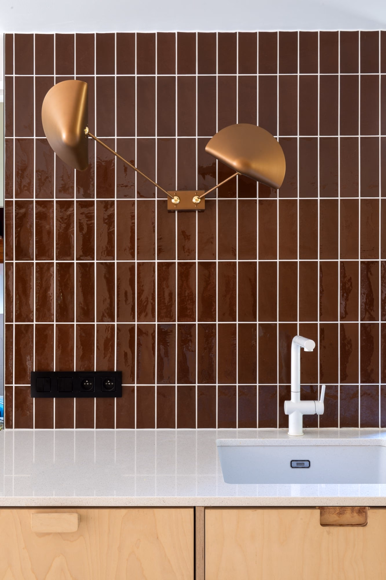 A bathroom with brown tiles and a white washbasin