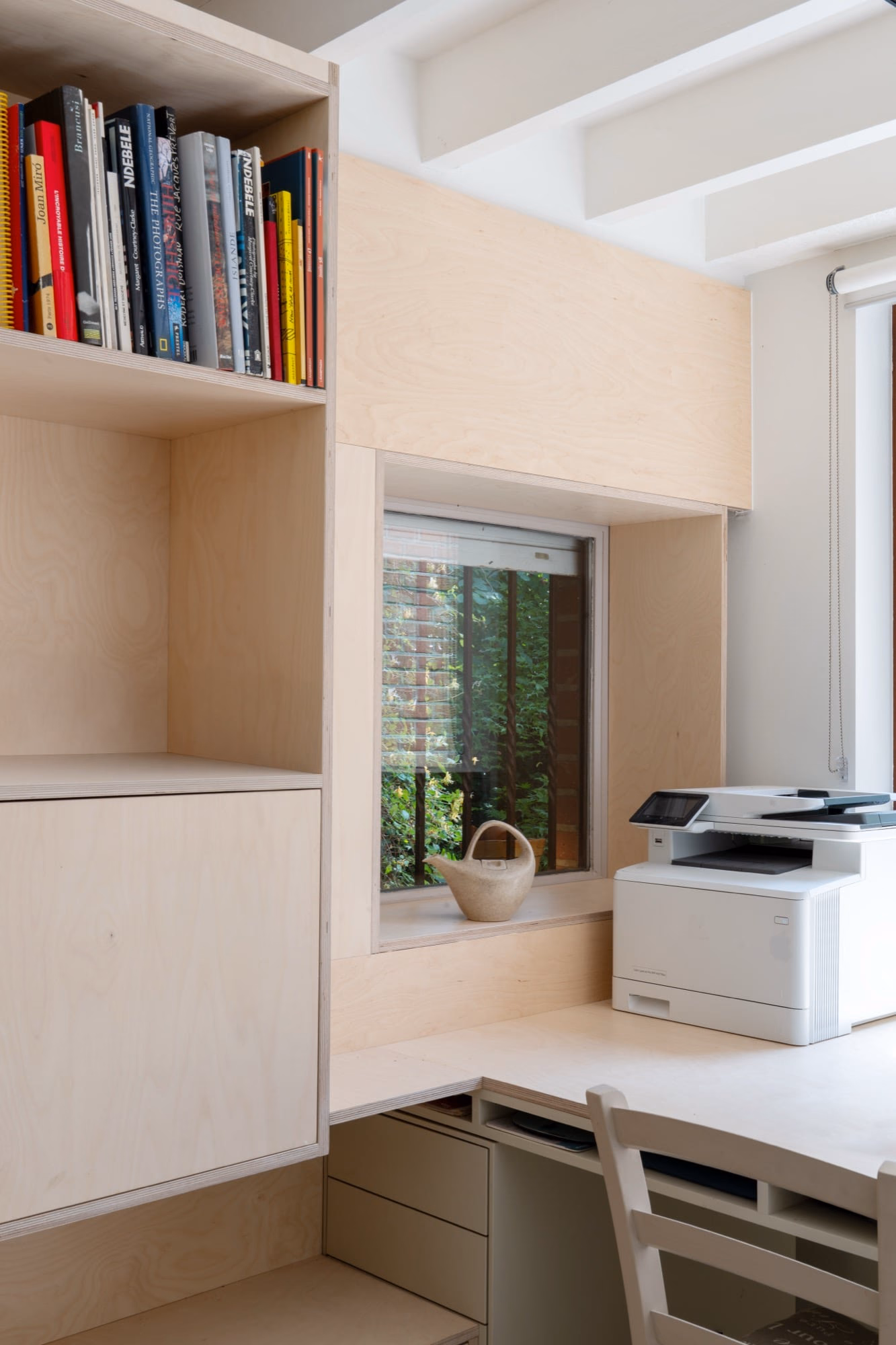 A printer on a desk beside a window