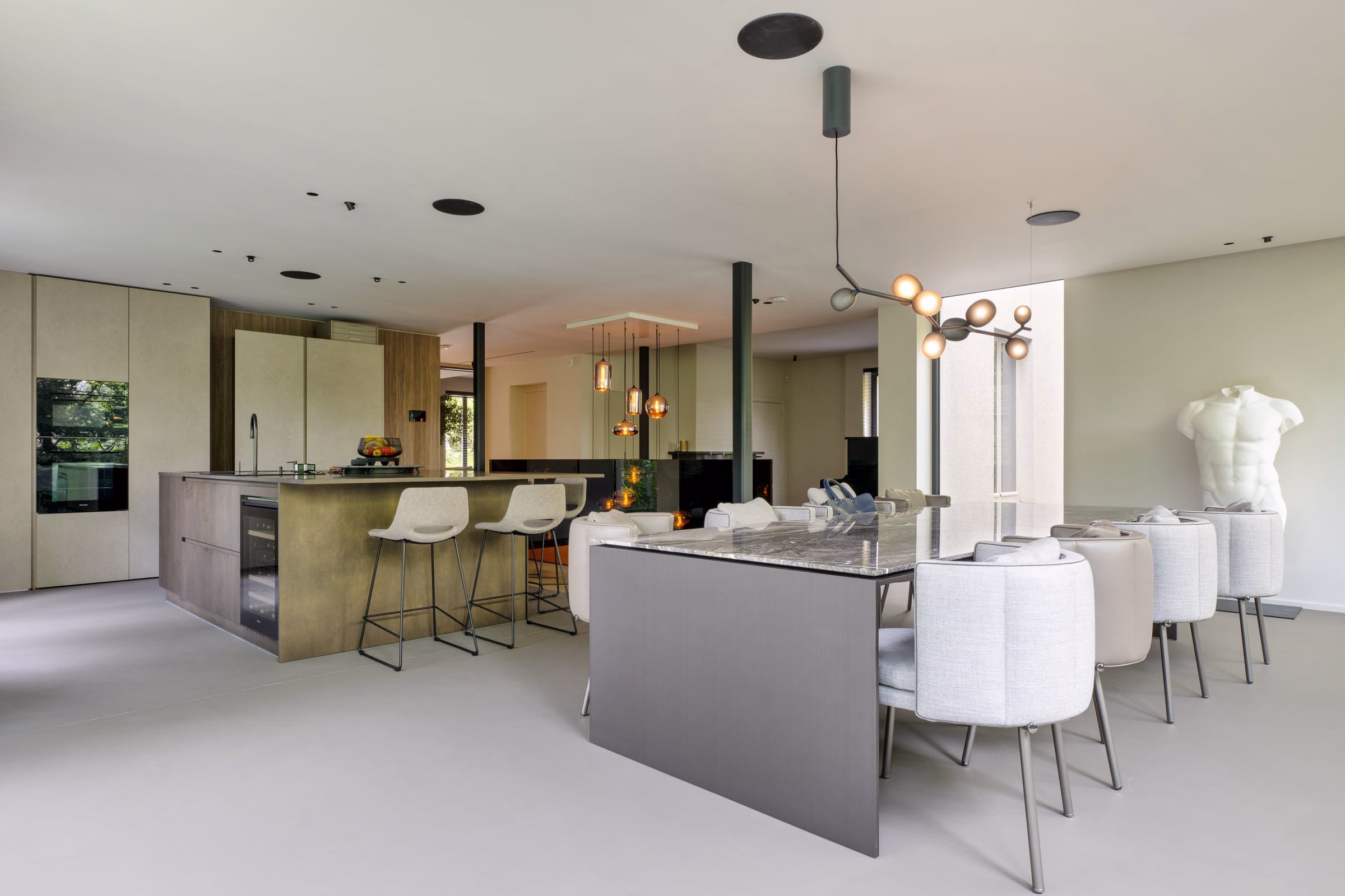 A kitchen with a marble worktop and white chairs