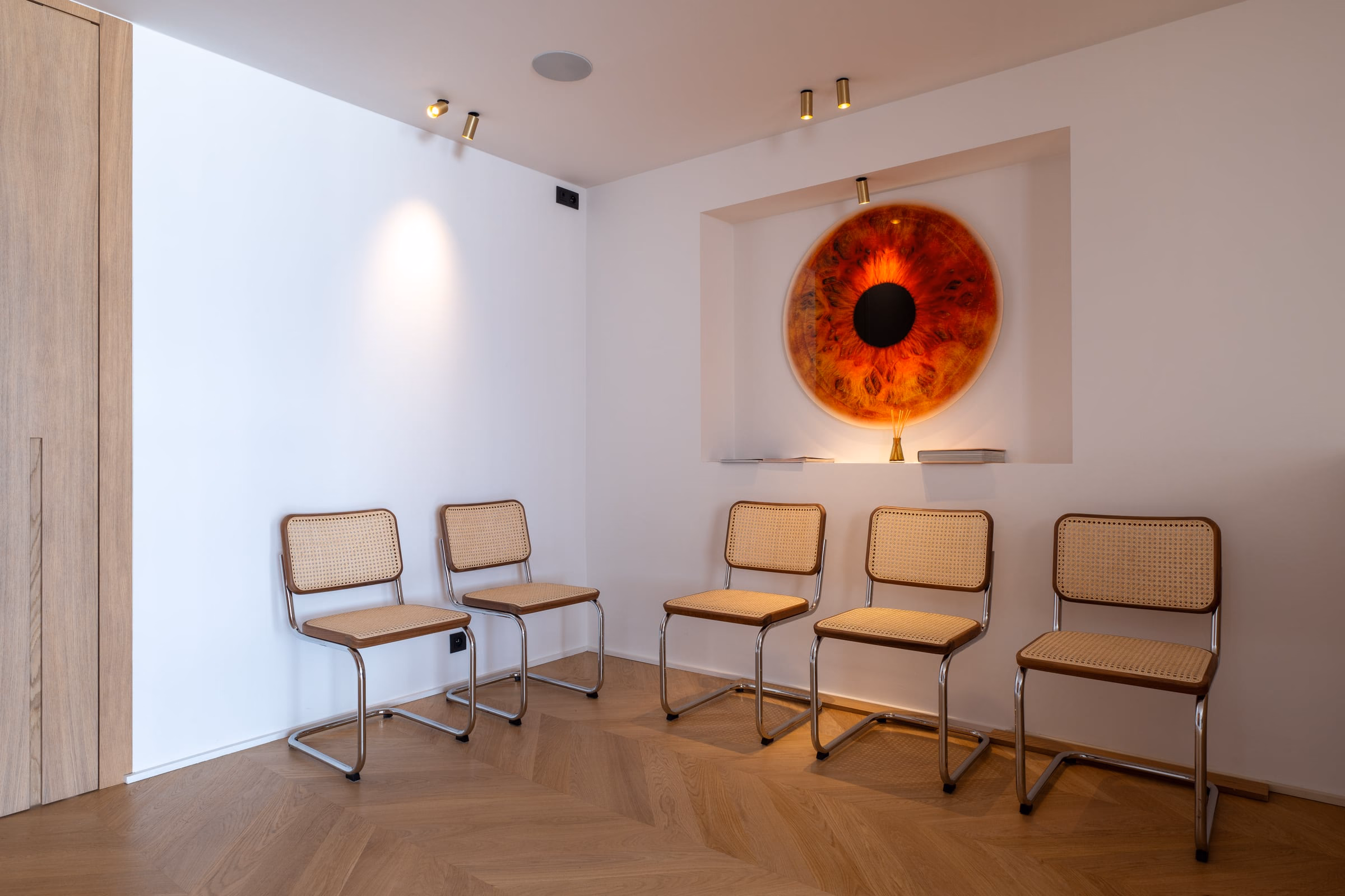 A room with chairs and a painting of an eye