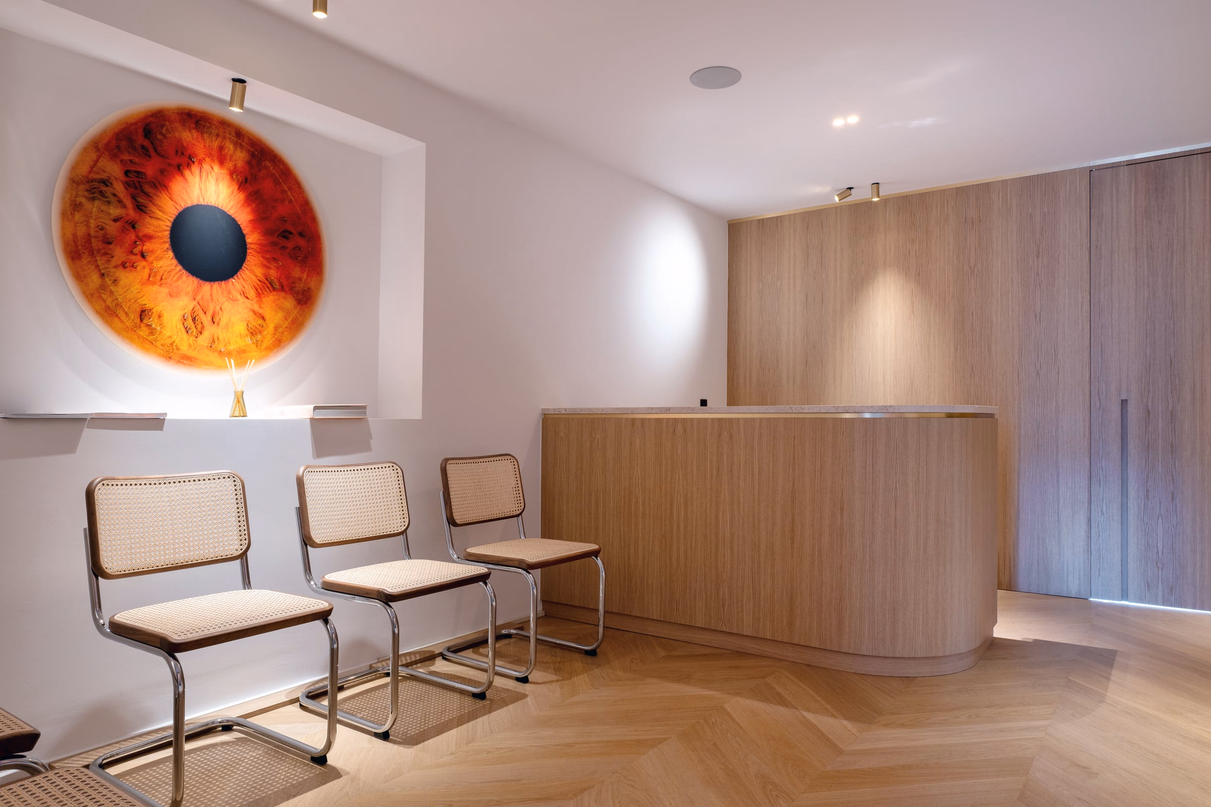 A waiting room with chairs and a painting of an eye