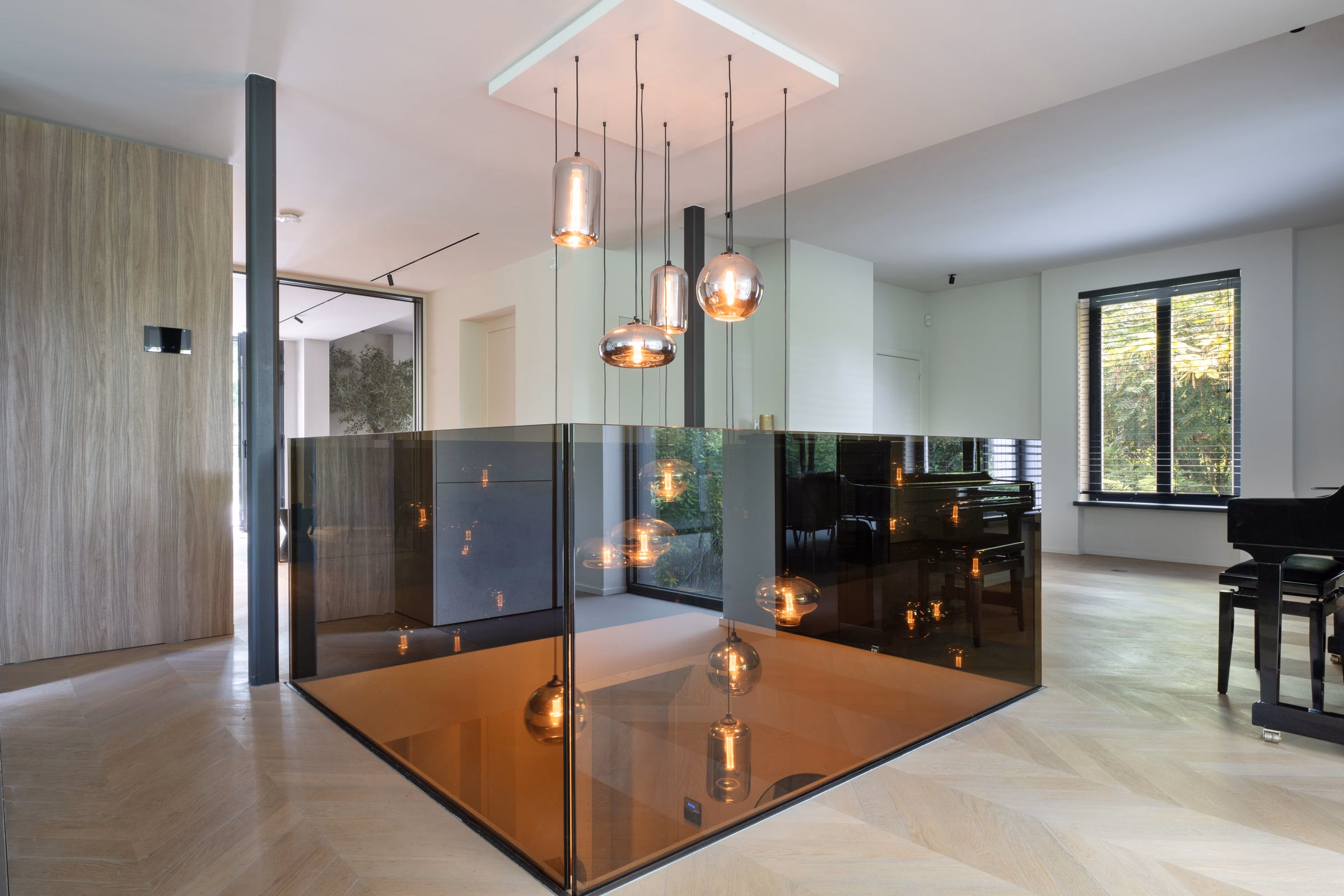 A staircase with a glass balustrade beneath pendant lights