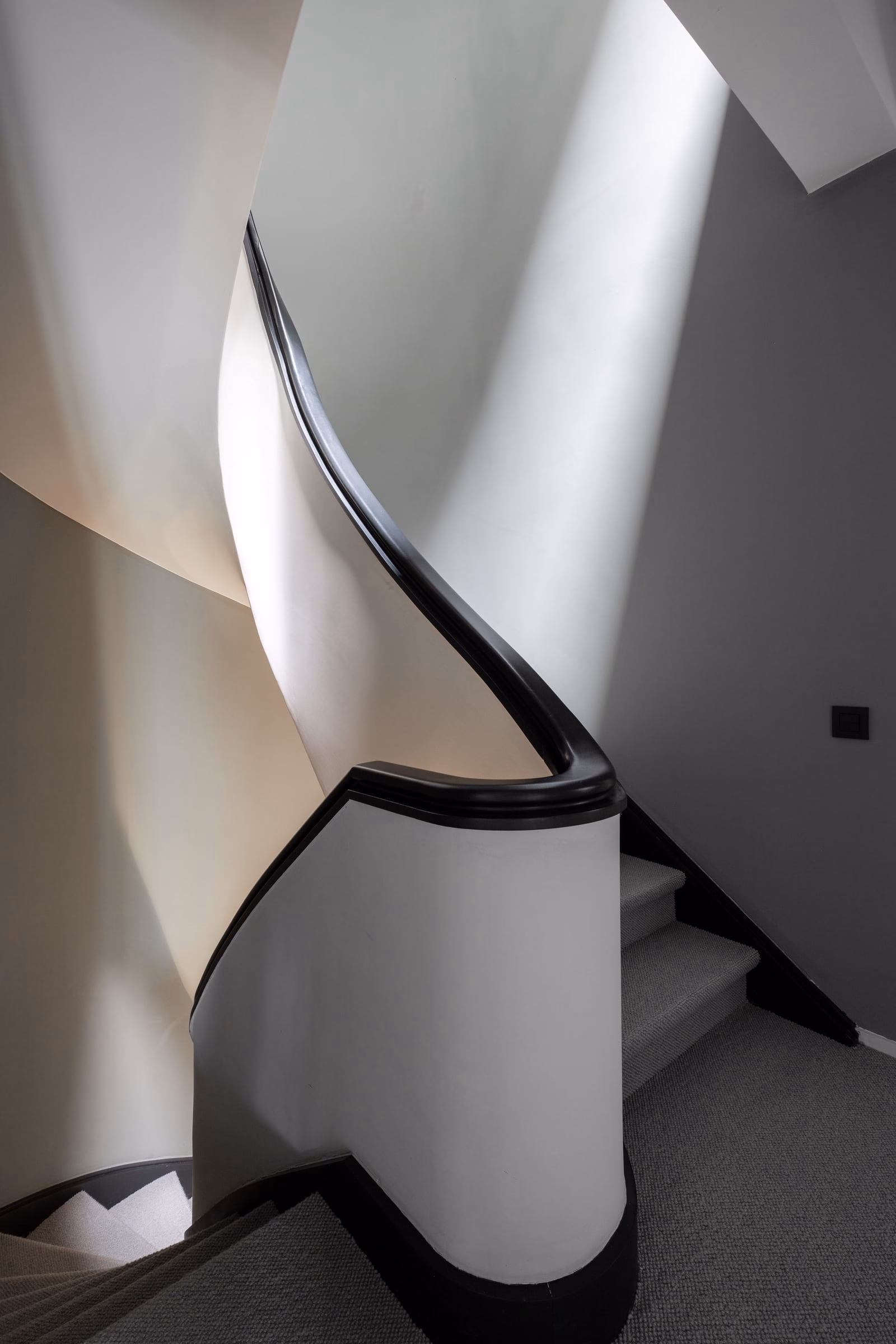 A spiral staircase with a black railing and white steps